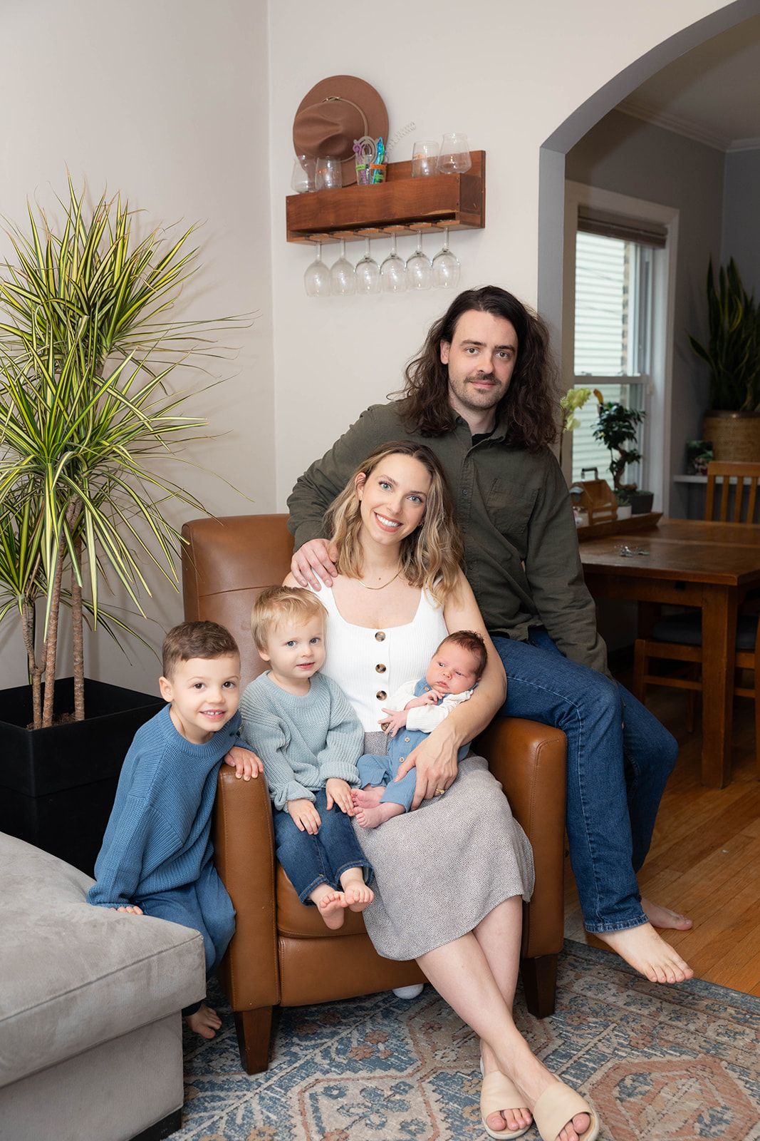 Family portrait in modern living room with parents and three young children.