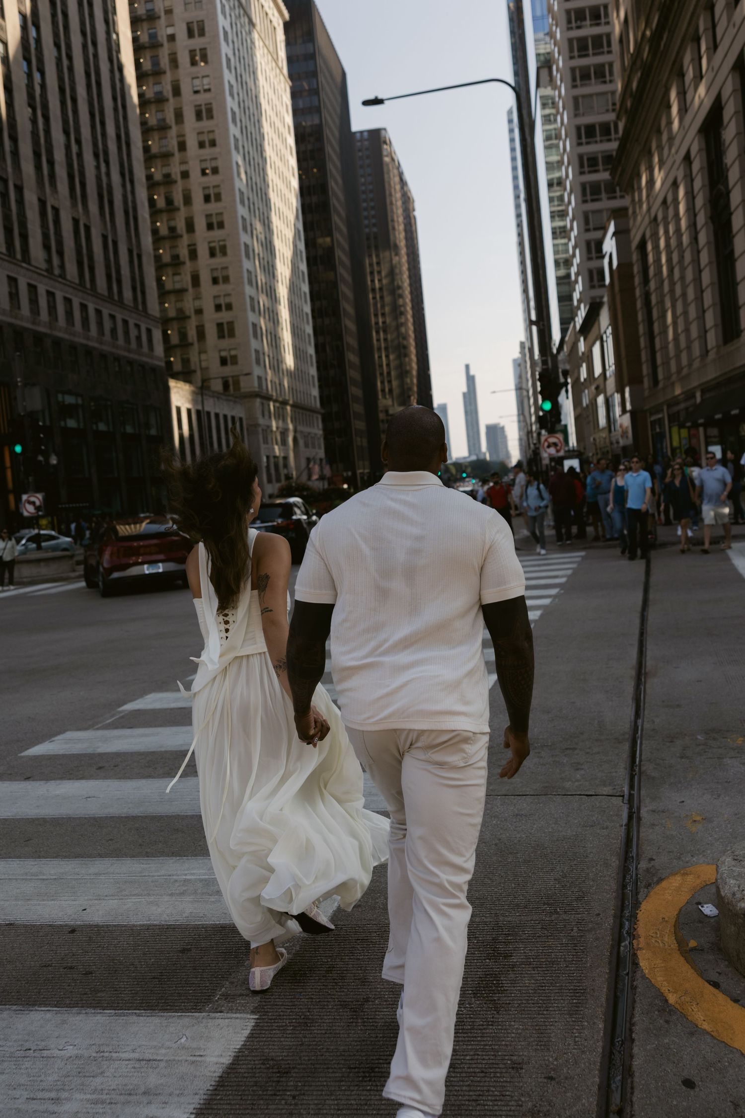 Two people in white clothing walk down a Chicago city street.