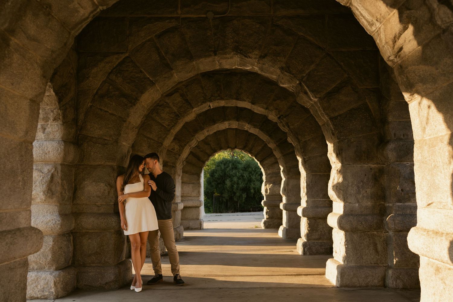 Stone archway corridor with dramatic lighting and shadows creating a romantic architectural setting.