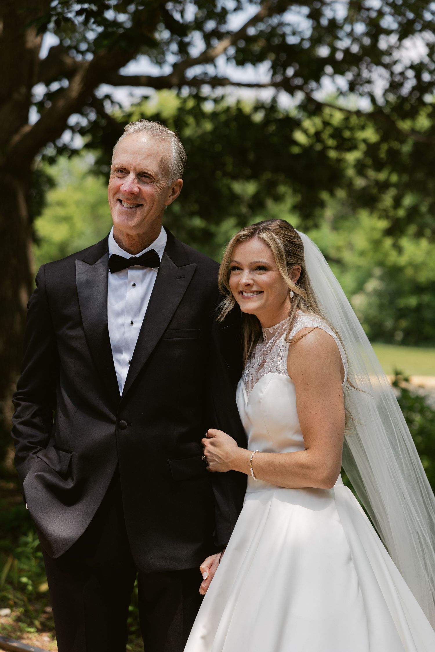 A joyful father-daughter moment on a wedding day in a garden setting.