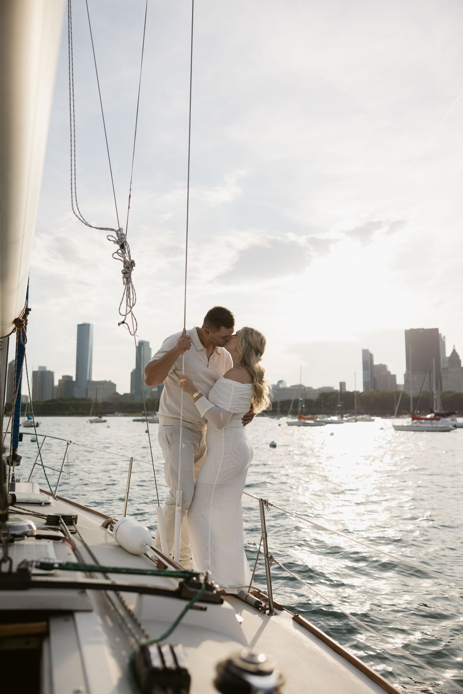 A romantic sailboat engagement photoshoot with the city skyline glowing in golden hour light.