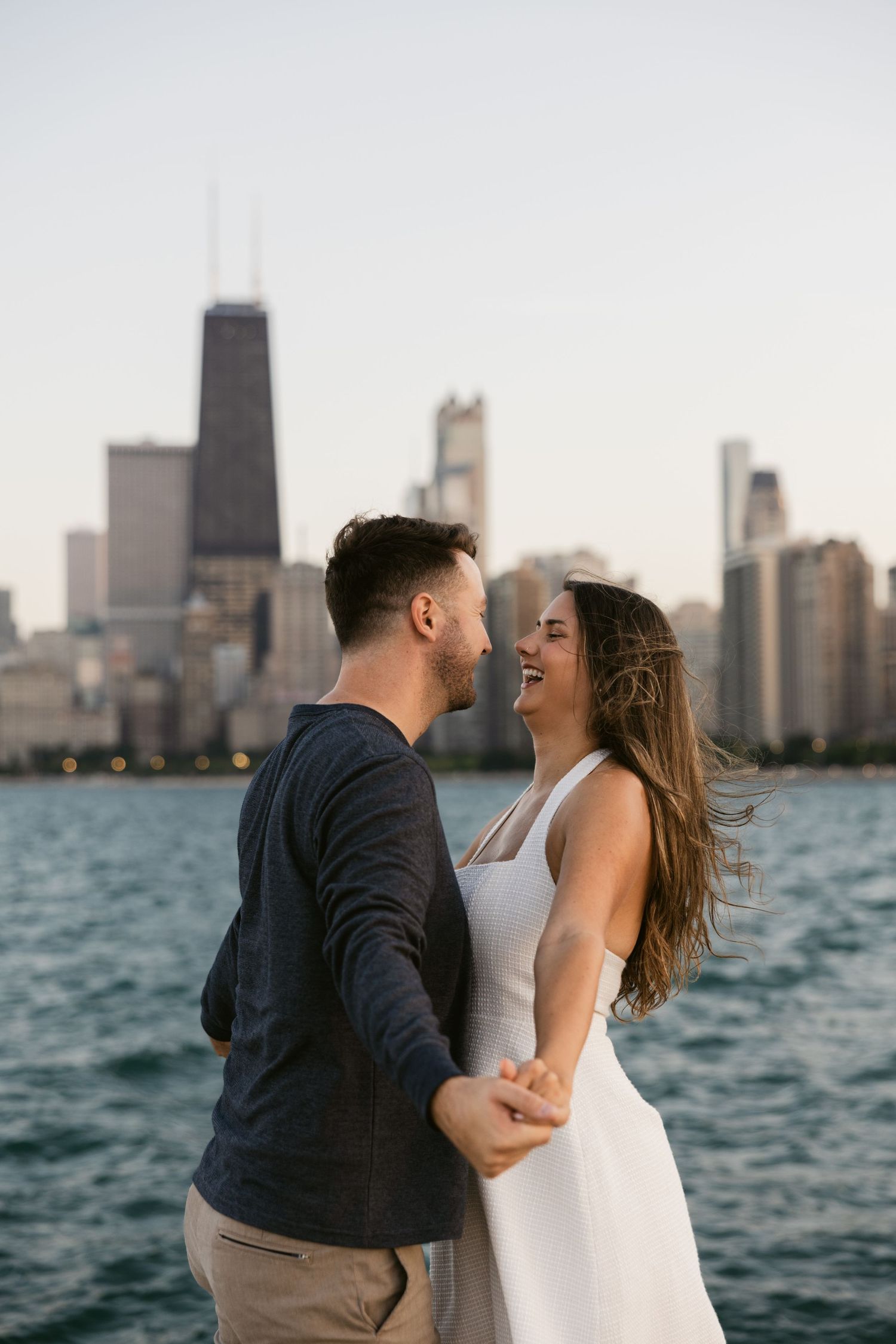 A couple embraces by Lake Michigan with Chicago's iconic skyline in the background.