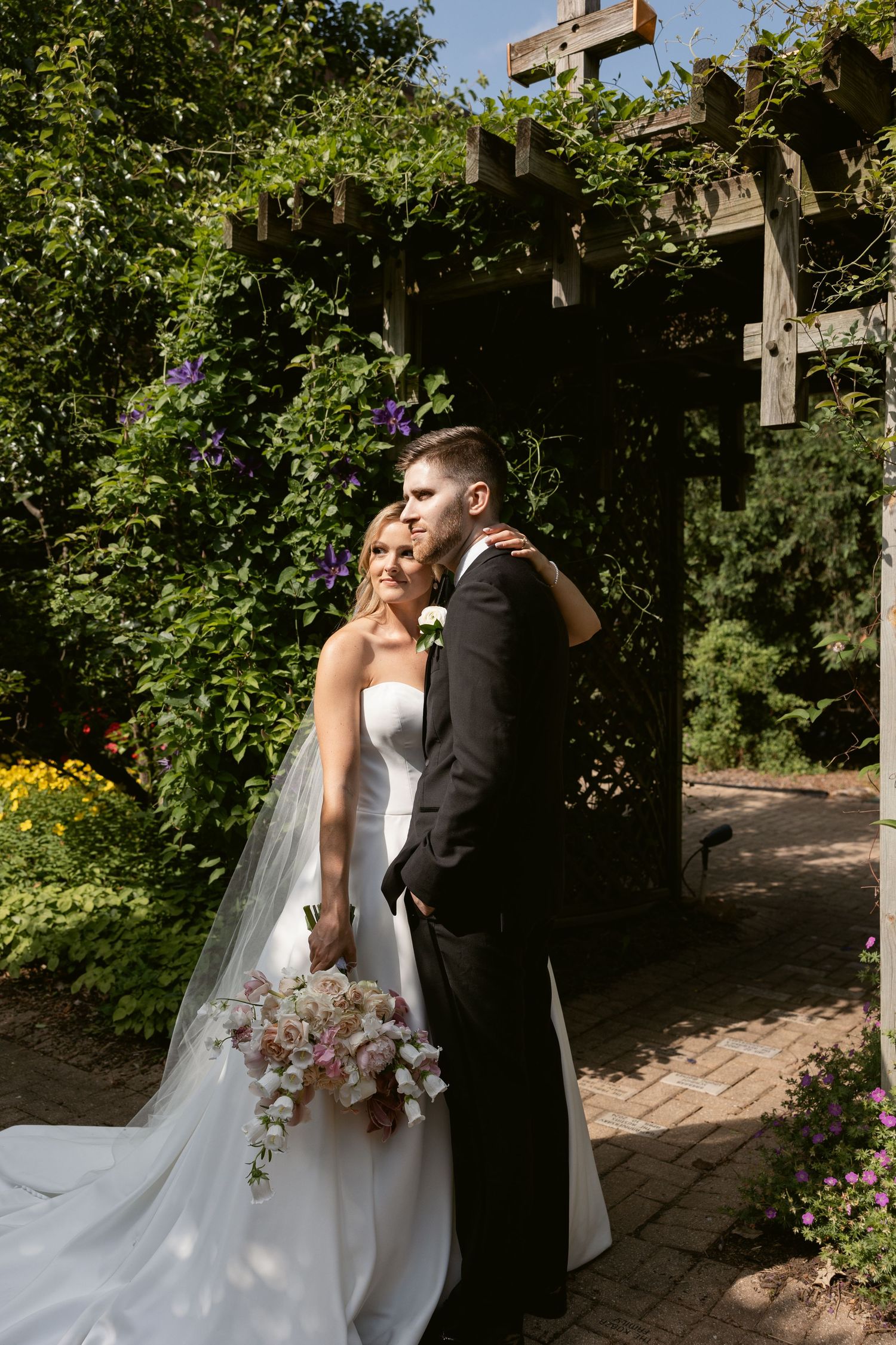 Happy couple sharing romantic moments in a lush garden pergola setting during their wedding celebration.