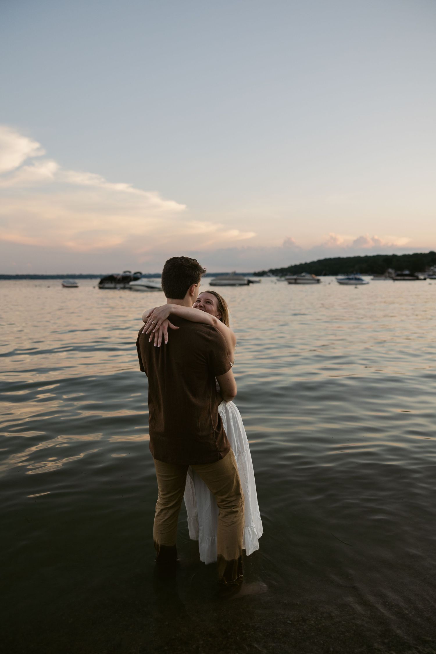 Silhouetted couple sharing an embrace at the water's edge during a sunset on the beach.