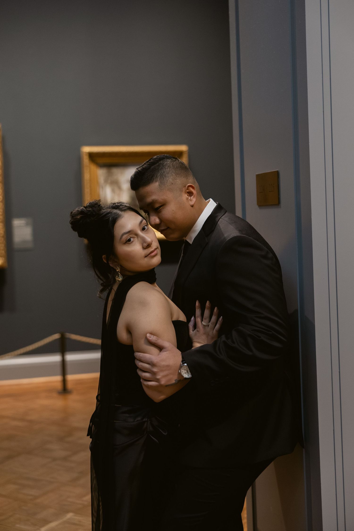Intimate moment captured in dark art gallery setting with wooden floors.
