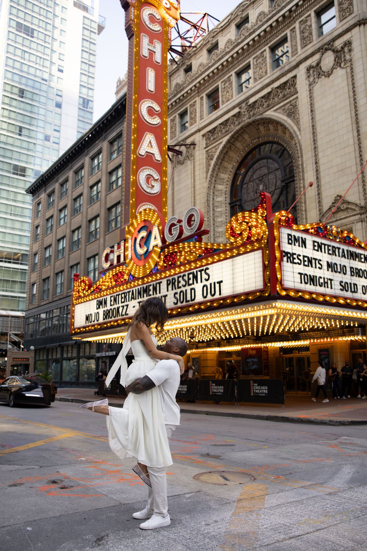 Dance poses captured in front of Chicago Theater with iconic illuminated marquee sign.