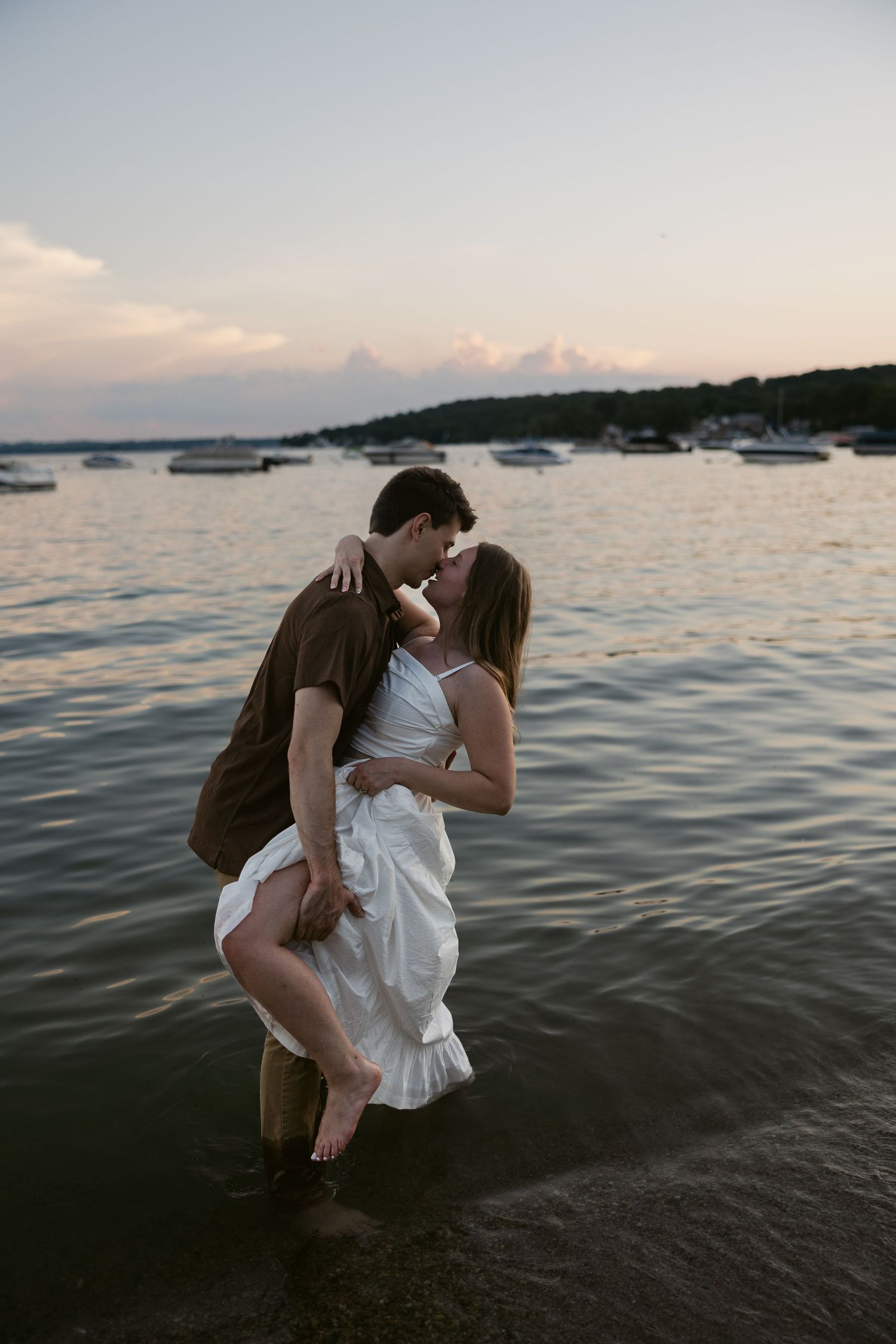 A romantic seaside moment captured between two people wading in shallow water at dusk.