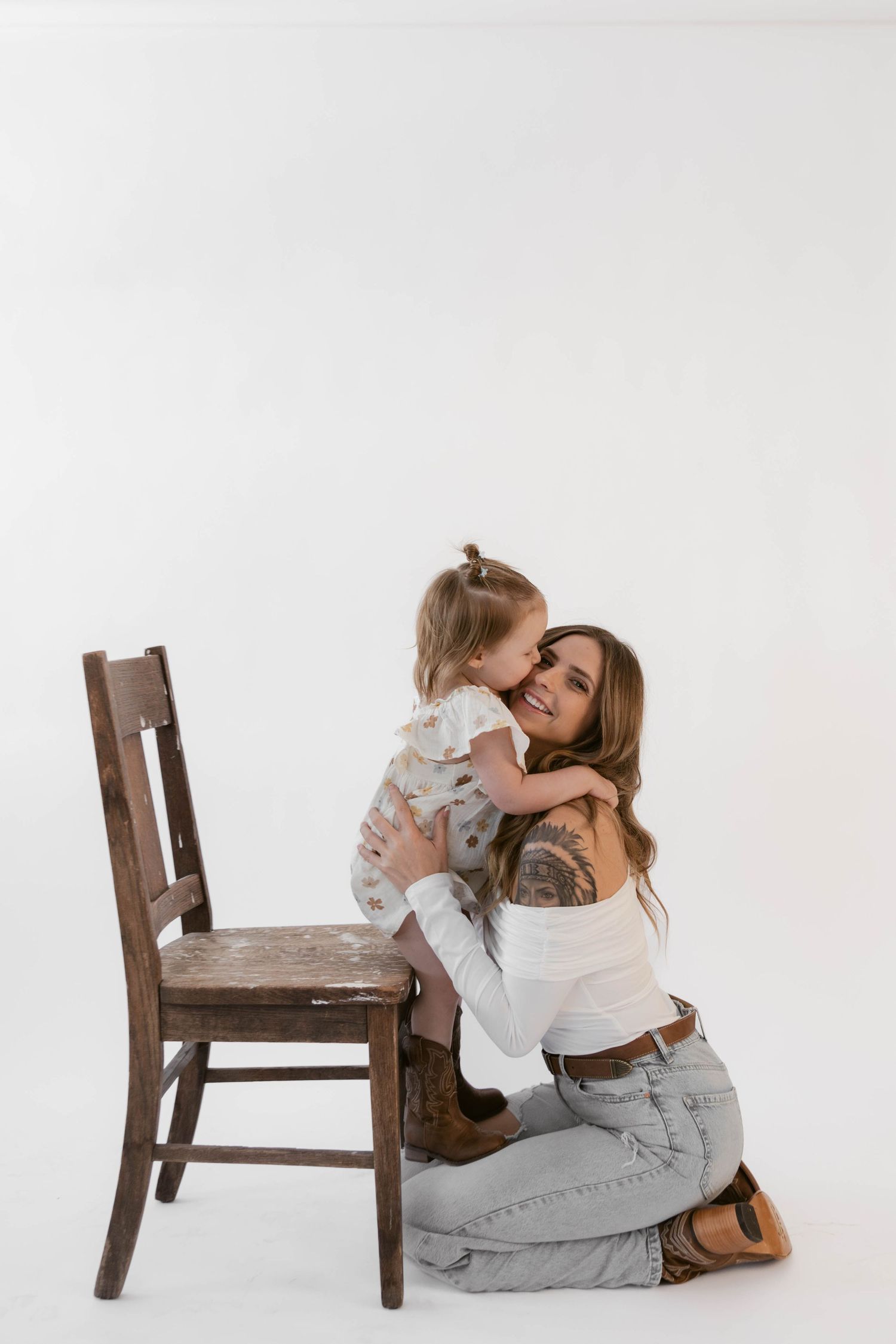 Tender moment between mother and child during studio photoshoot against white background.
