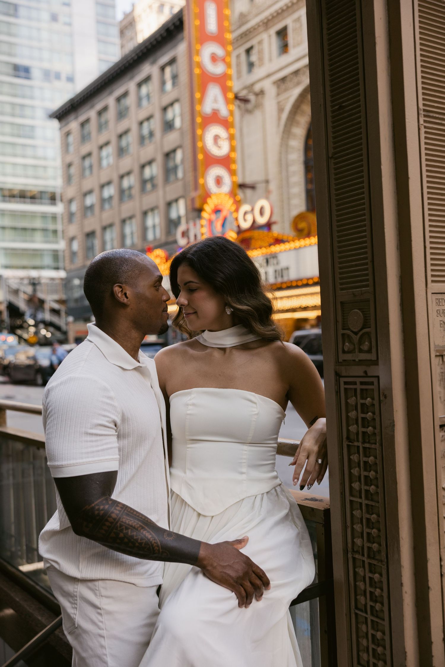 A couple embraces intimately in front of a historic Chicago theater with vintage signs visible.