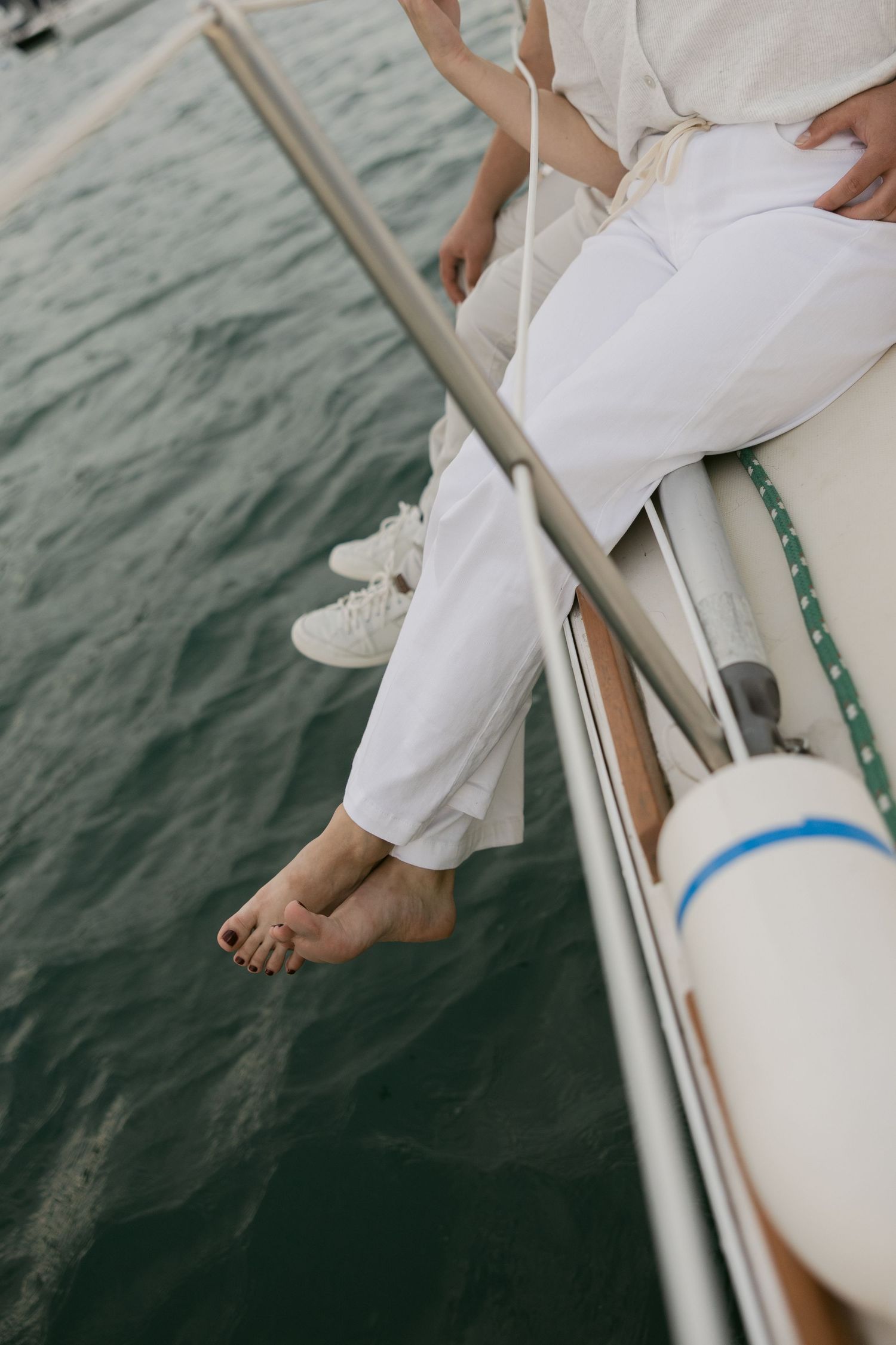 Close-up sequence of feet dangling over the edge of a boat above rippling ocean water.