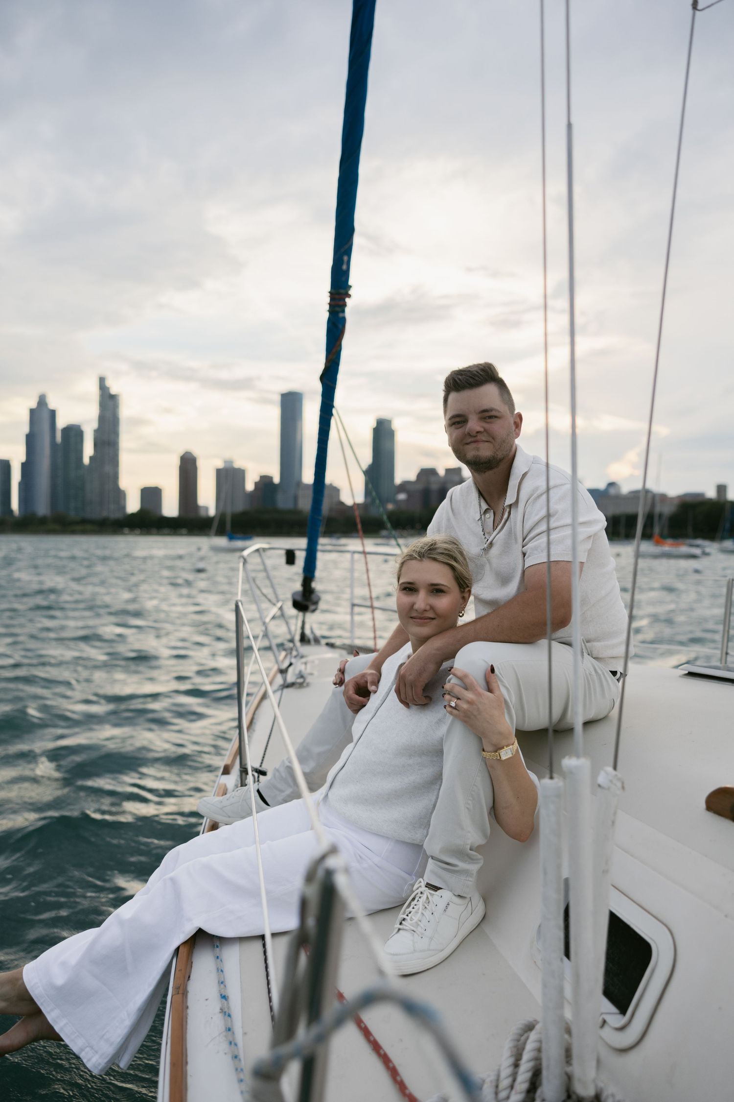 Casual sailing date with a couple in white clothing against an urban waterfront backdrop.