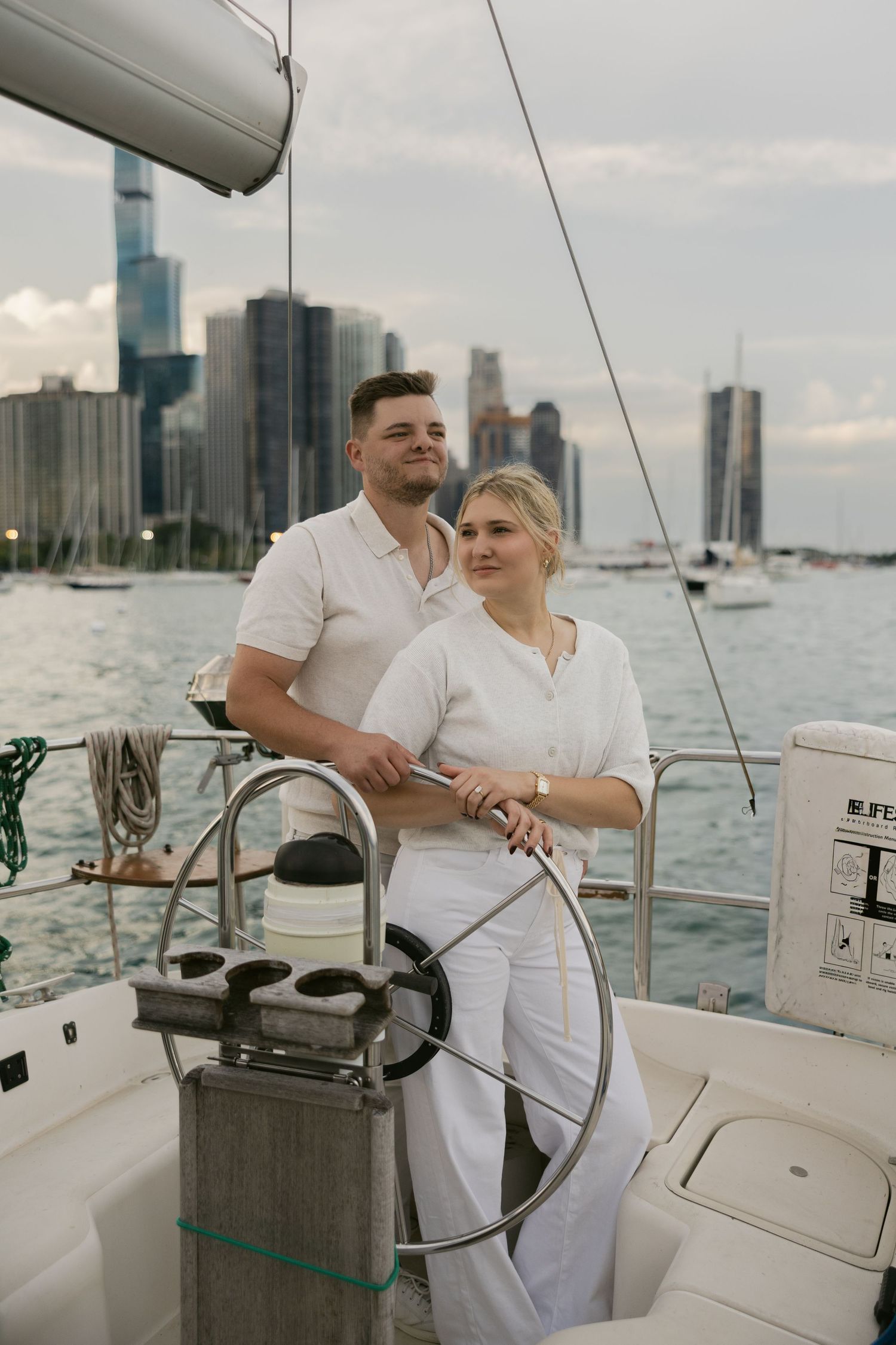 Couple sailing together on a yacht with downtown skyscrapers visible across the water.