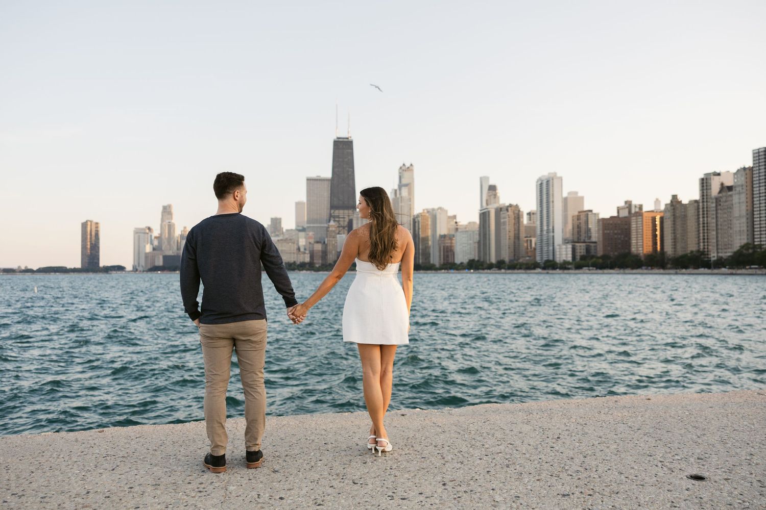 Couple walking along Chicago's North Avenue Beach with the city skyline in the background.