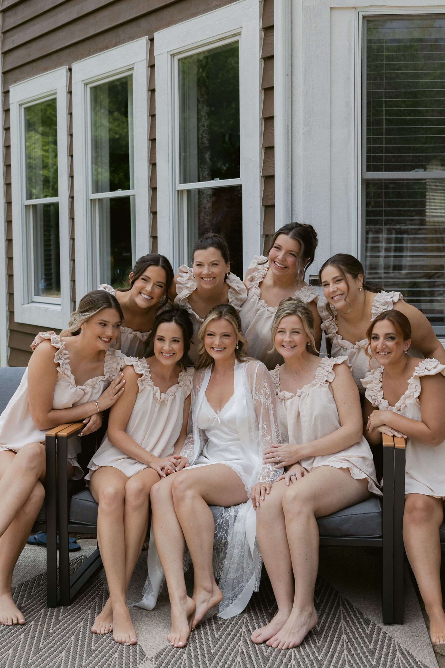A group wearing white and cream colored outfits sitting together on a wooden porch.