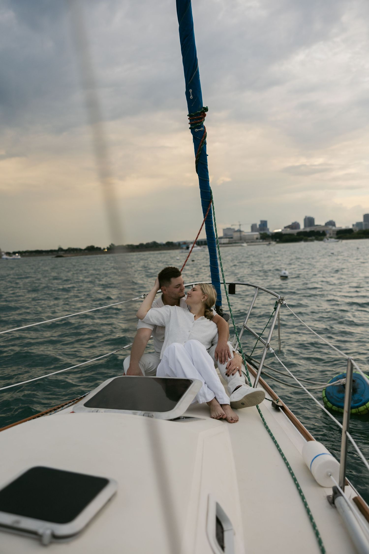 Sunset sailing photoshoot with couple against serene waterfront backdrop.