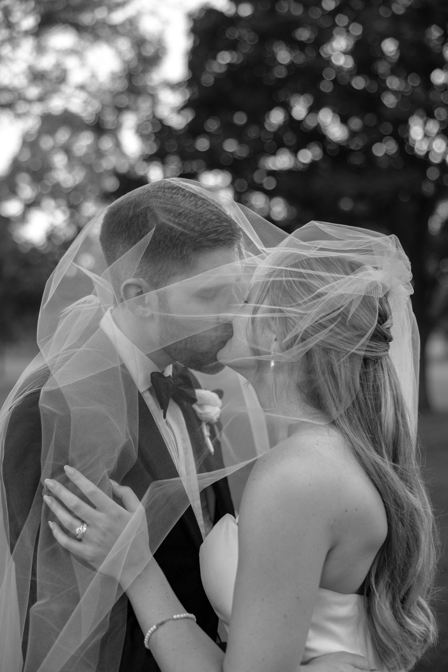Ethereal black and white photo of wedding couple with flowing veil creating artistic movement.