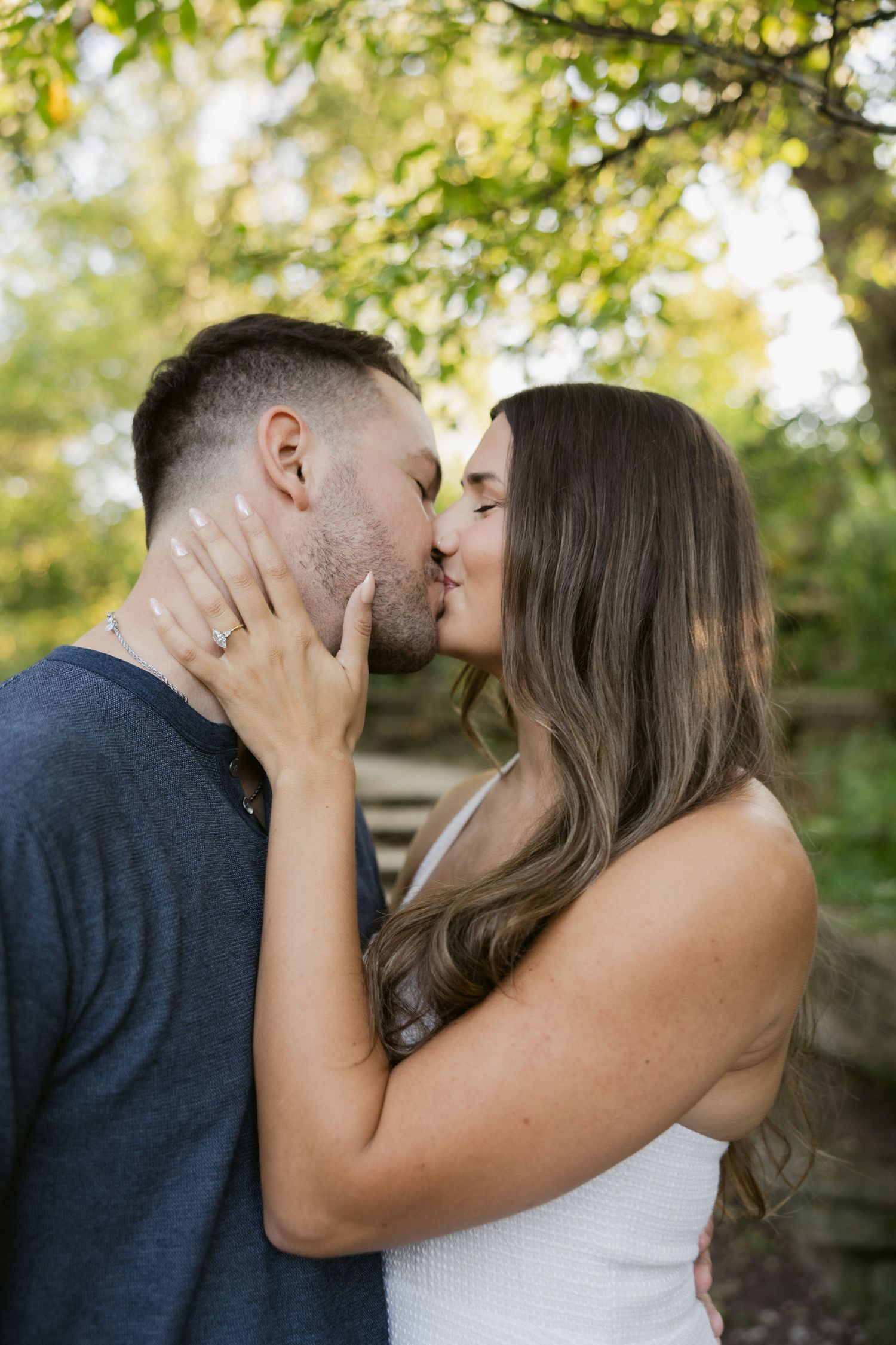 A romantic embrace shared between a couple against a natural outdoor background with soft lighting.