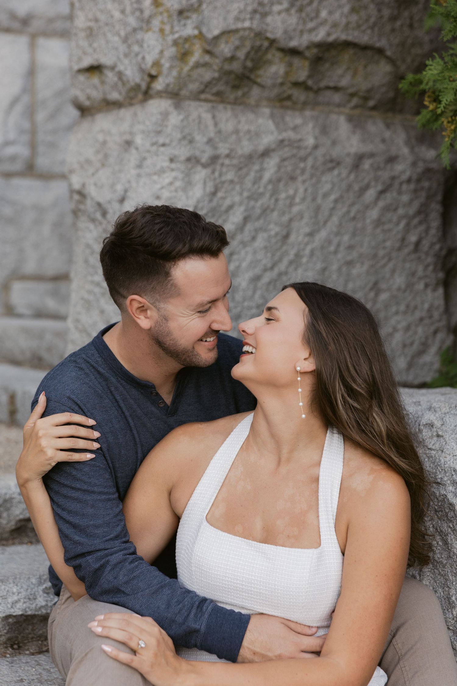 Intimate portrait session against a textured stone wall backdrop in natural lighting.