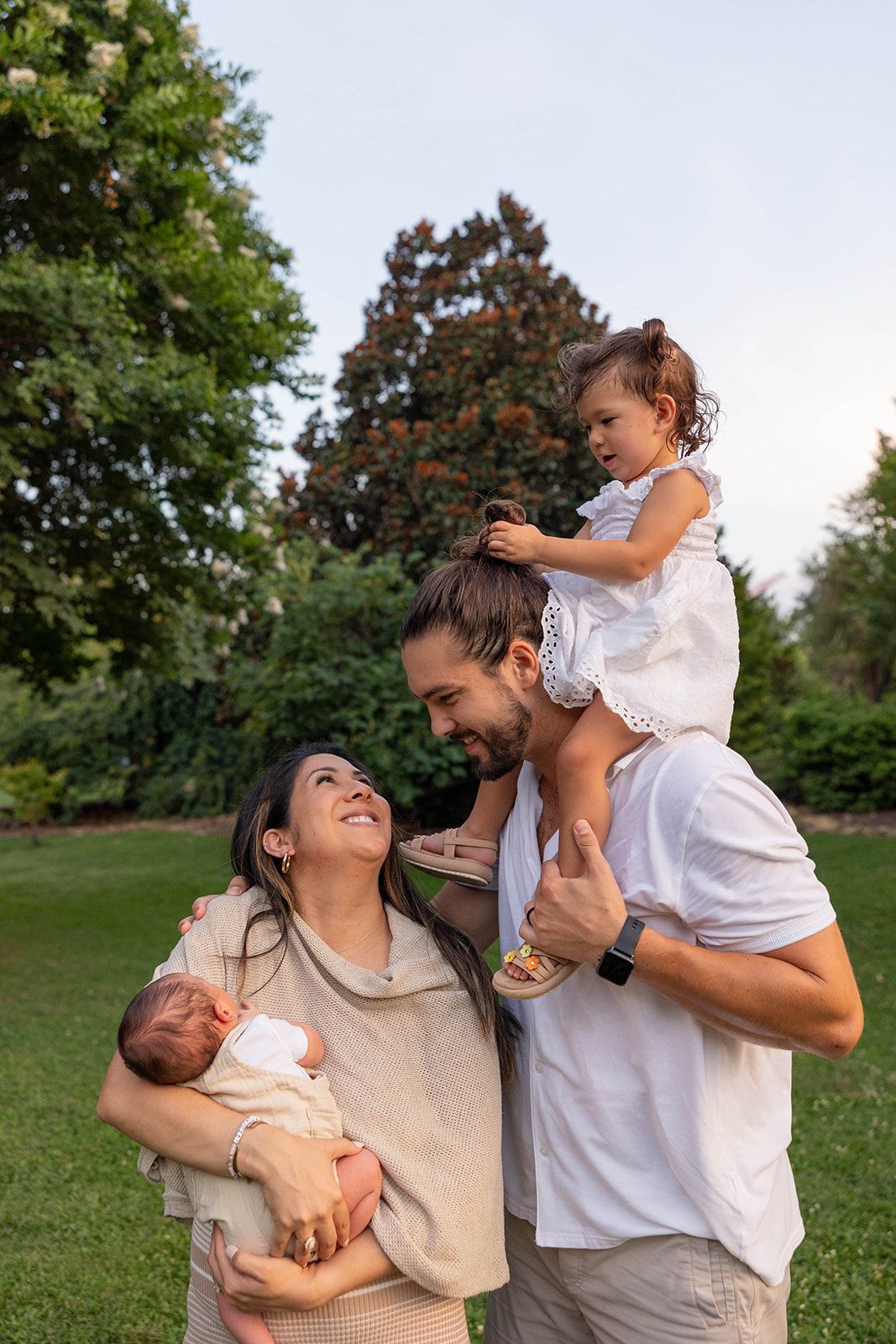 A happy family shares laughter and embraces while enjoying time together in a park setting.
