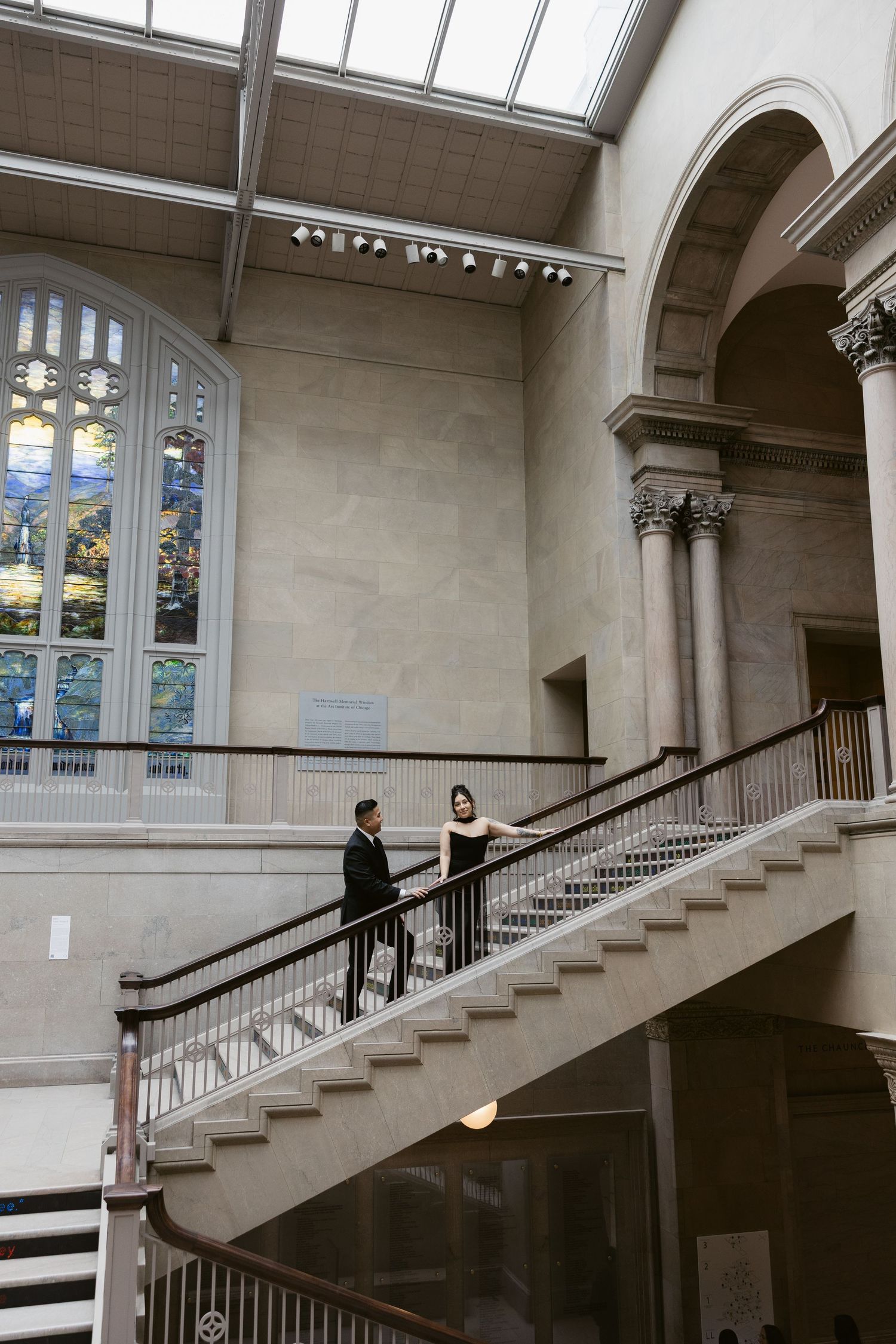 A grand staircase with arched windows and natural light in a classical museum interior.