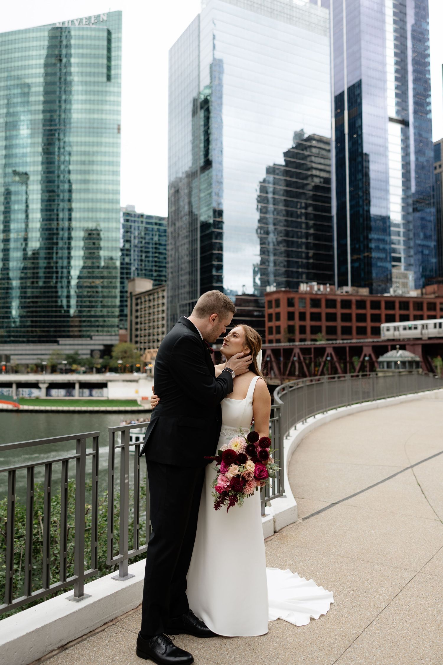 A romantic wedding couple shares intimate moments on a bridge with Chicago's modern skyline as their backdrop.
