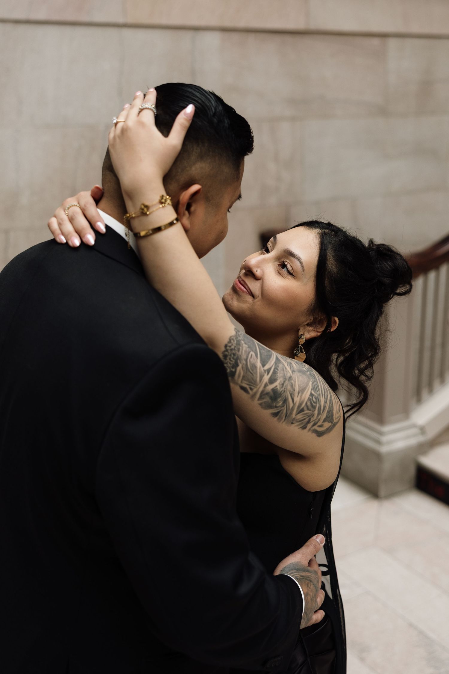 Intimate couple shares tender moments against a light stone wall background.