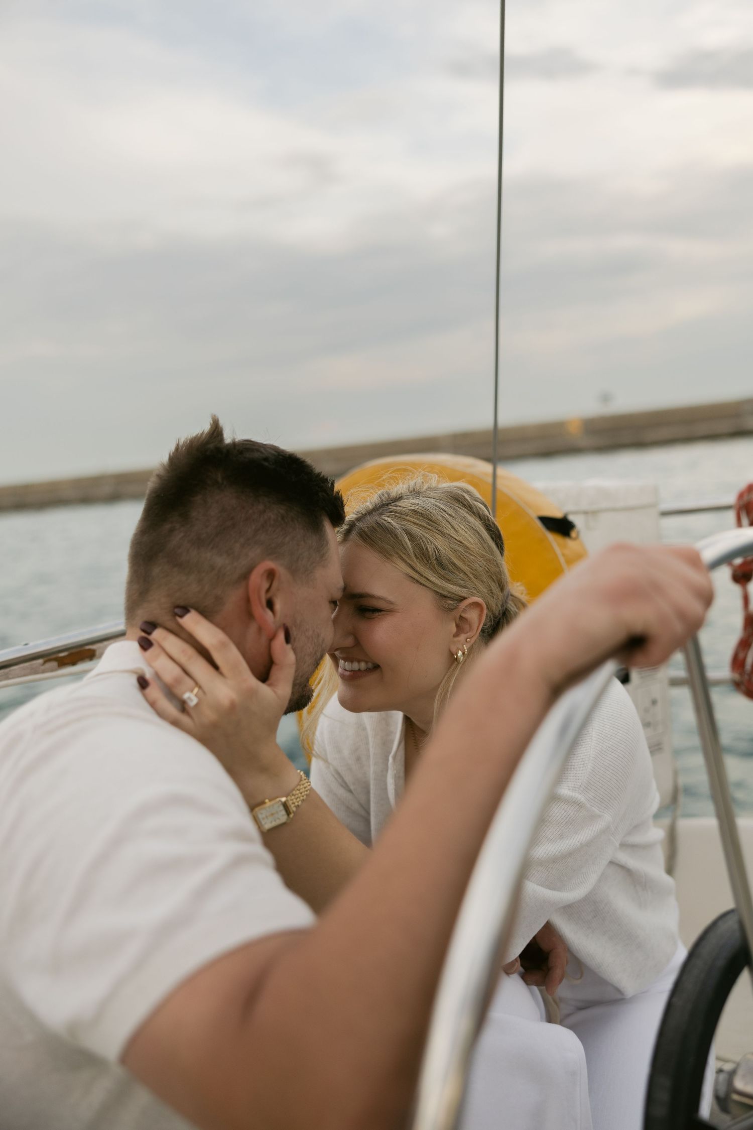 Intimate sailing moment with two people in white attire sharing a tender moment on a boat.
