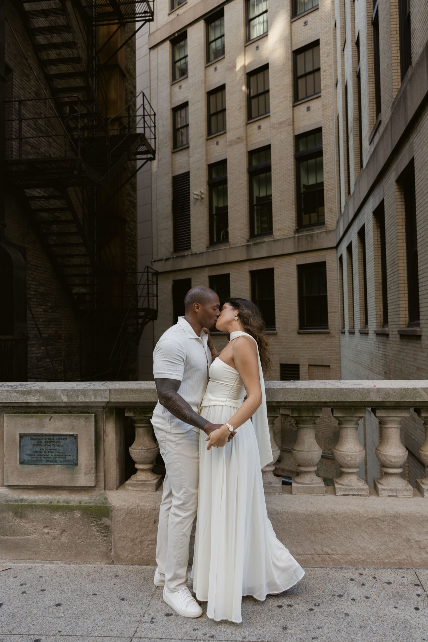 Urban wedding photography session against industrial building backdrop with stone balustrades.
