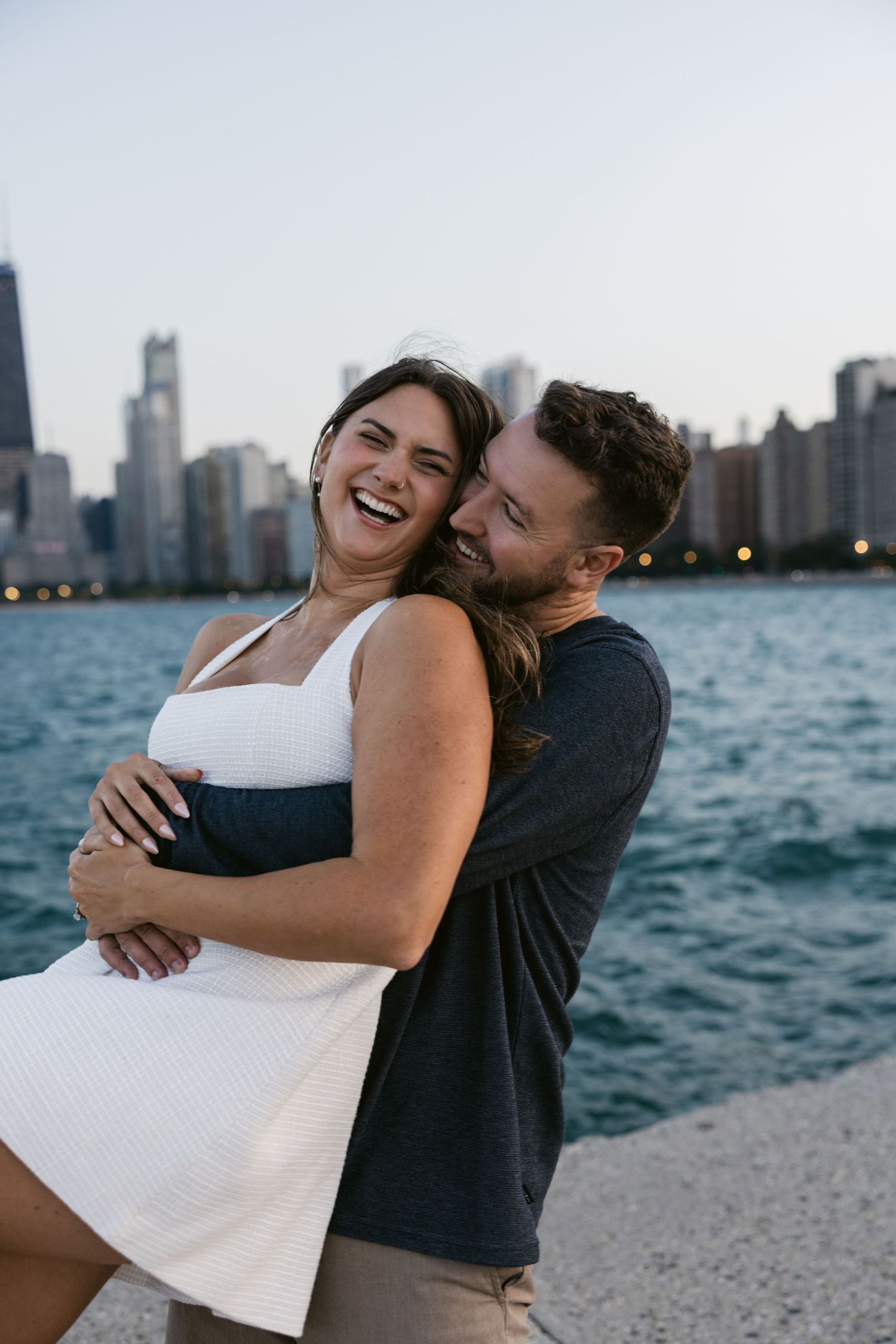 Happy couple sharing laughter and embraces against Chicago's waterfront backdrop.