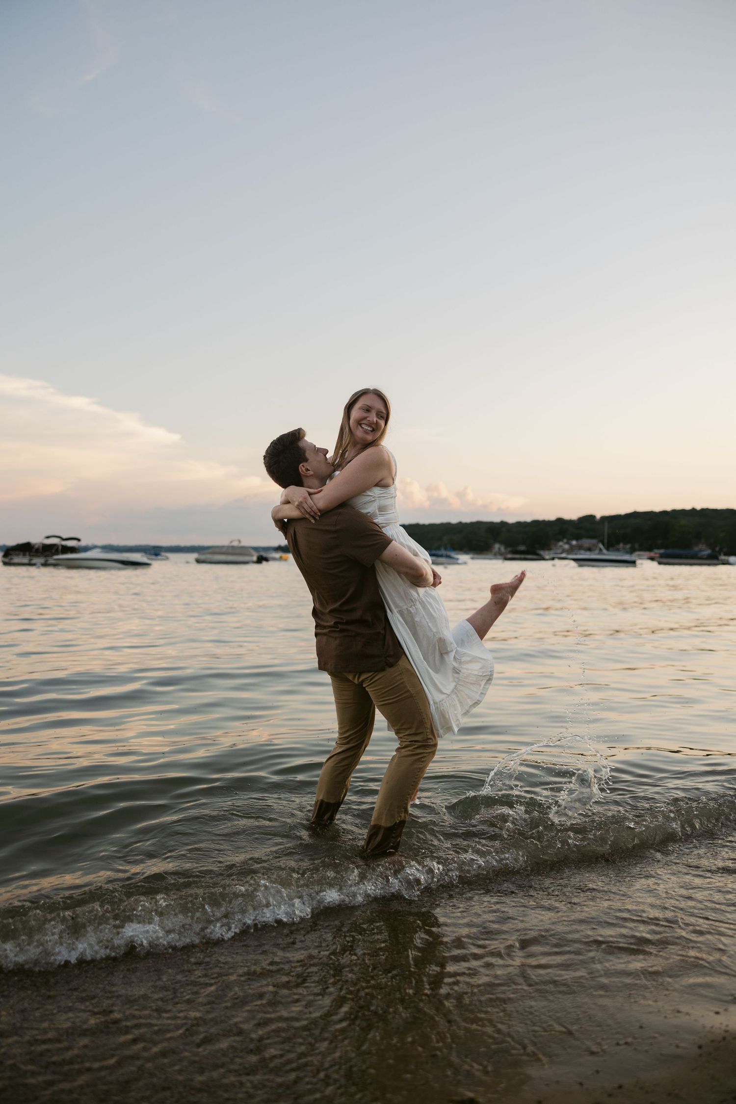 Couple plays in shallow water during sunset by the shore.