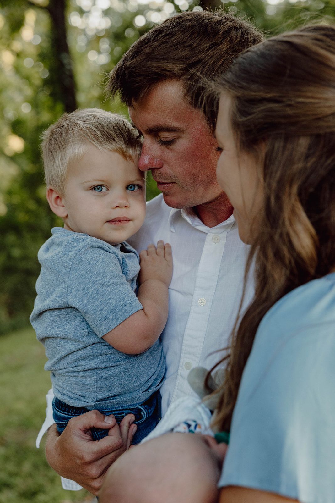 An intimate family portrait captured outdoors with soft natural lighting.