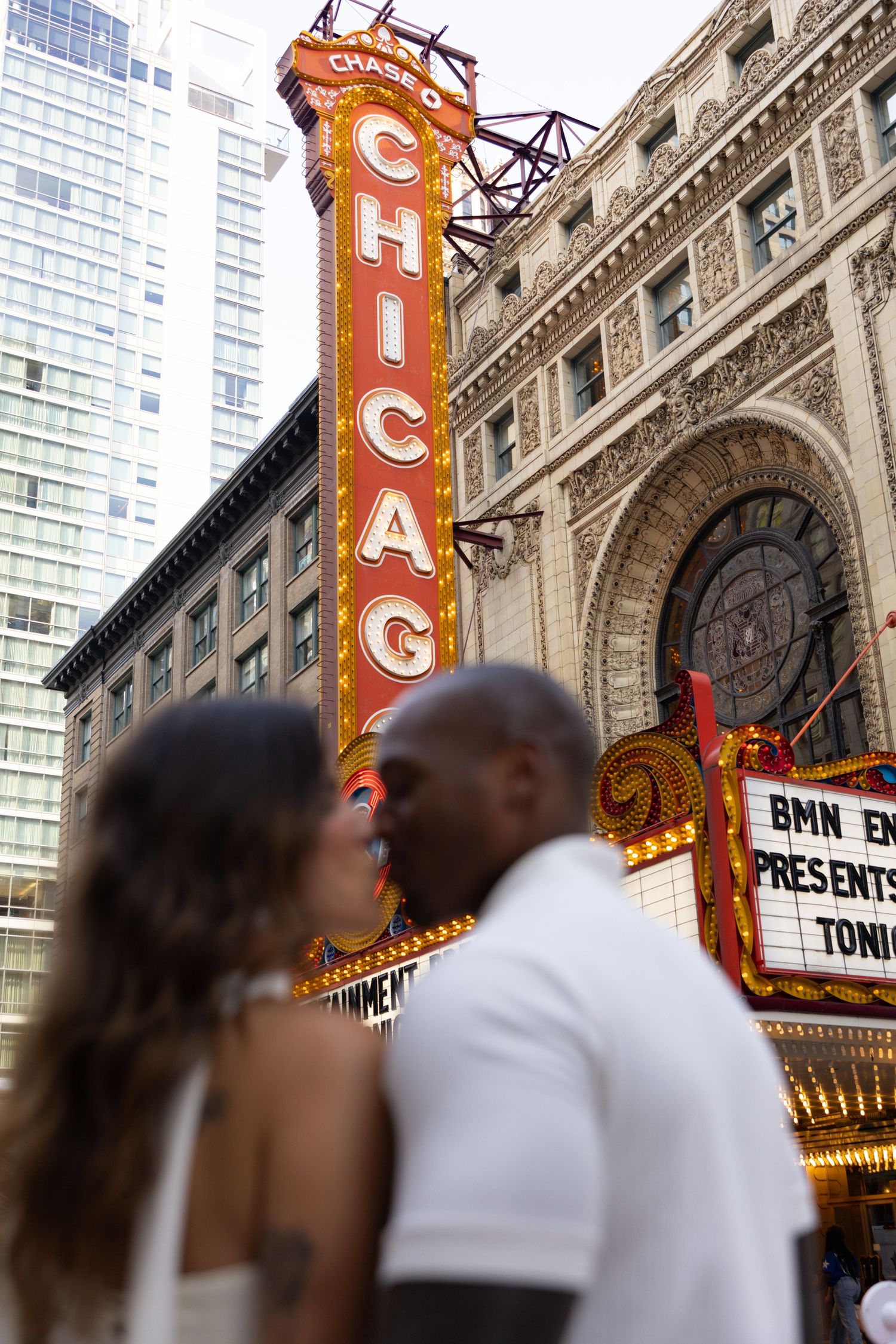 Silhouetted couple embracing in front of the glowing Chicago Theatre marquee.