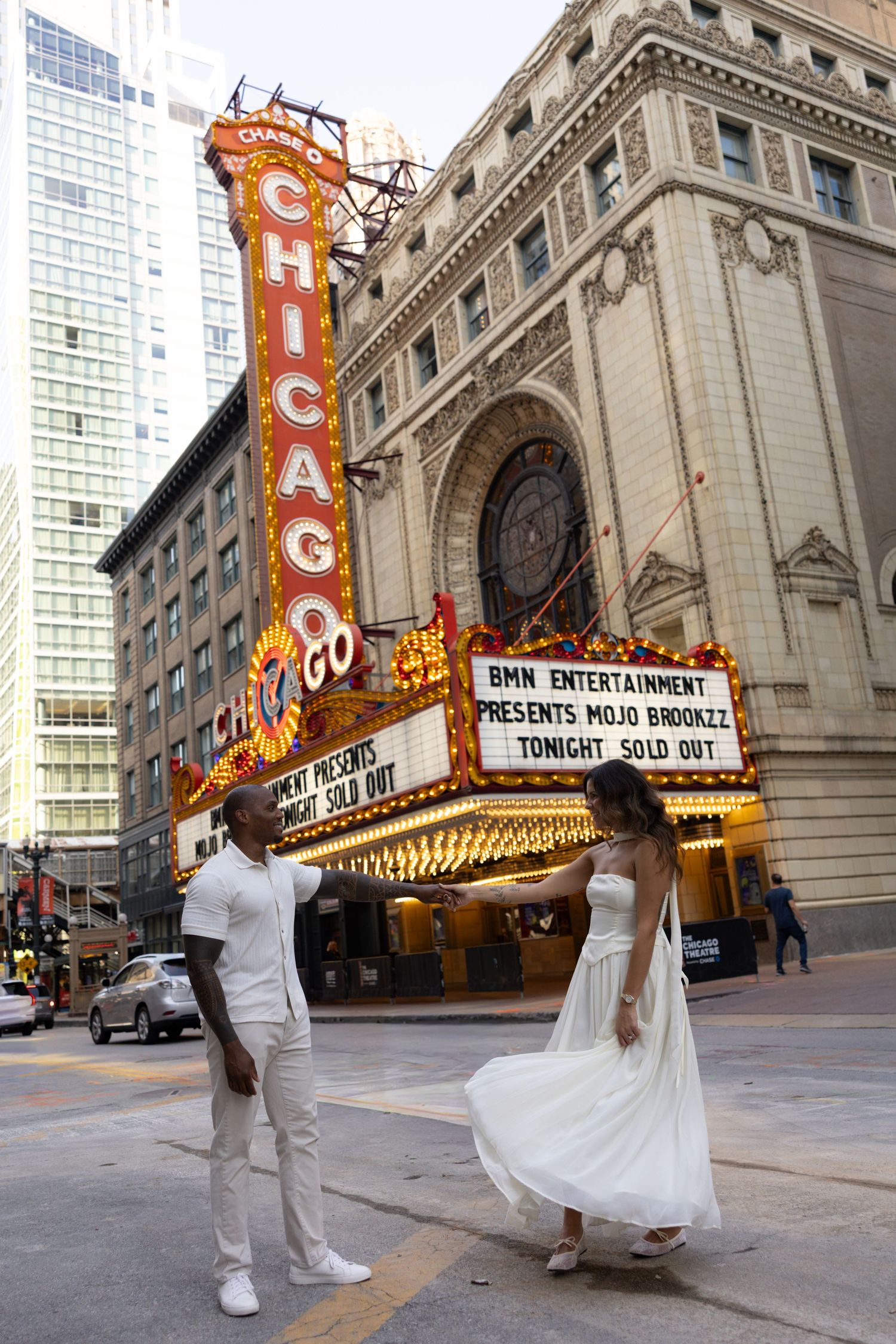 A couple performs a romantic dance move outside the historic Chicago Theatre.