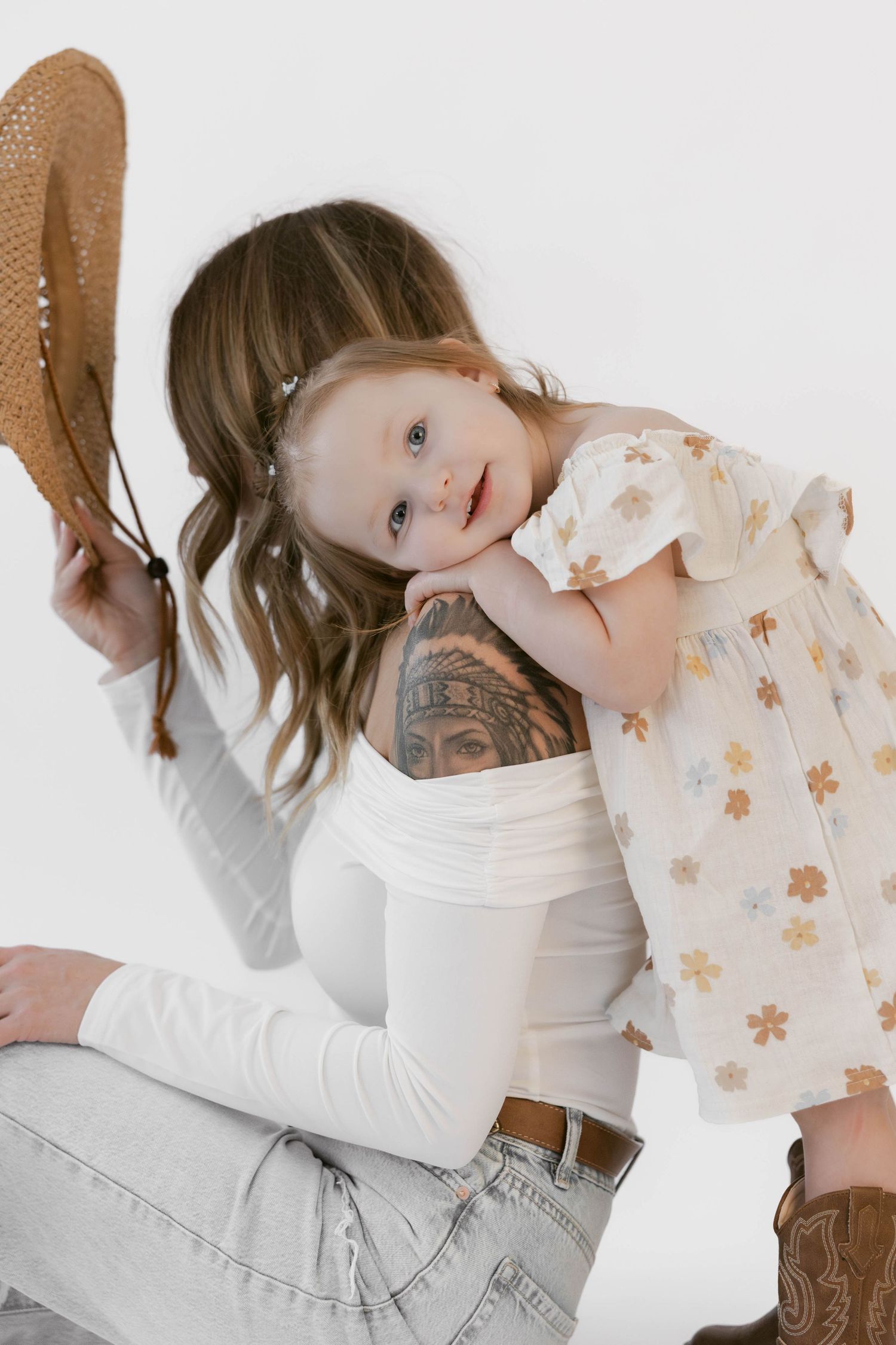Studio portraits capture sweet embraces and genuine emotion in western wear against white backdrop.