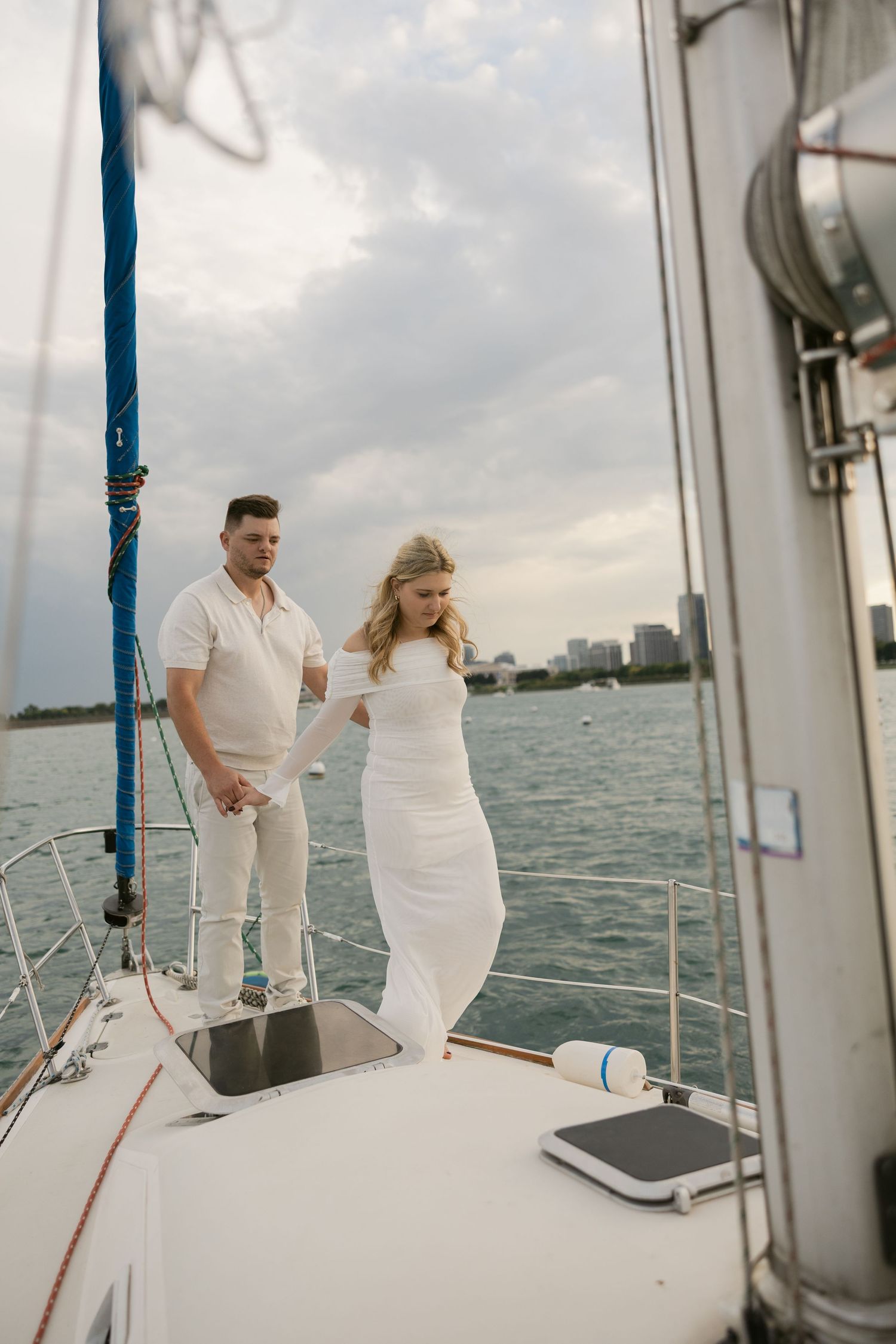 A boat photoshoot captures a couple in white attire against a waterfront skyline.