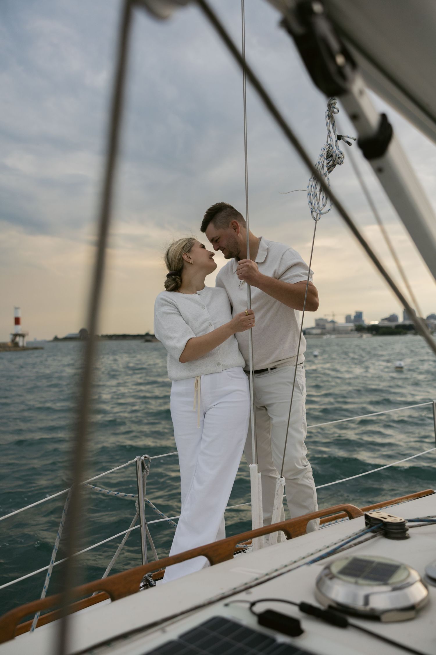 Romantic sailing photo shoot with cityscape in background at sunset.