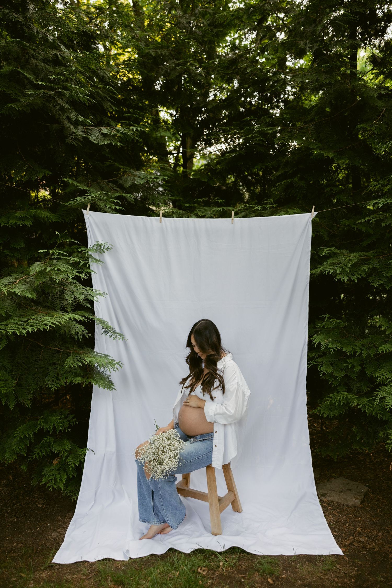 Creative pregnancy photoshoot poses on white backdrop in natural outdoor setting.