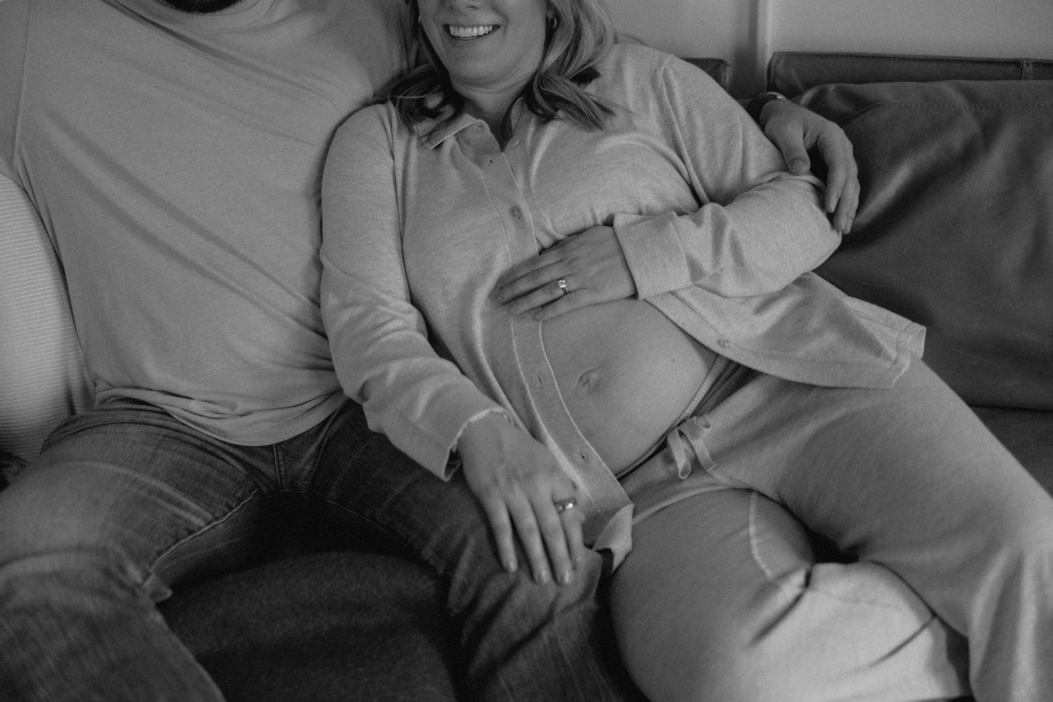 A couple rests together on a gray couch in casual attire.