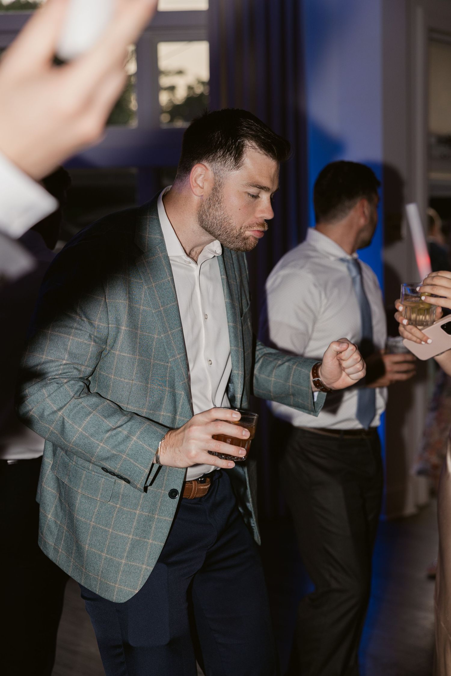 Guest in plaid blazer enjoying drinks at wedding reception party.