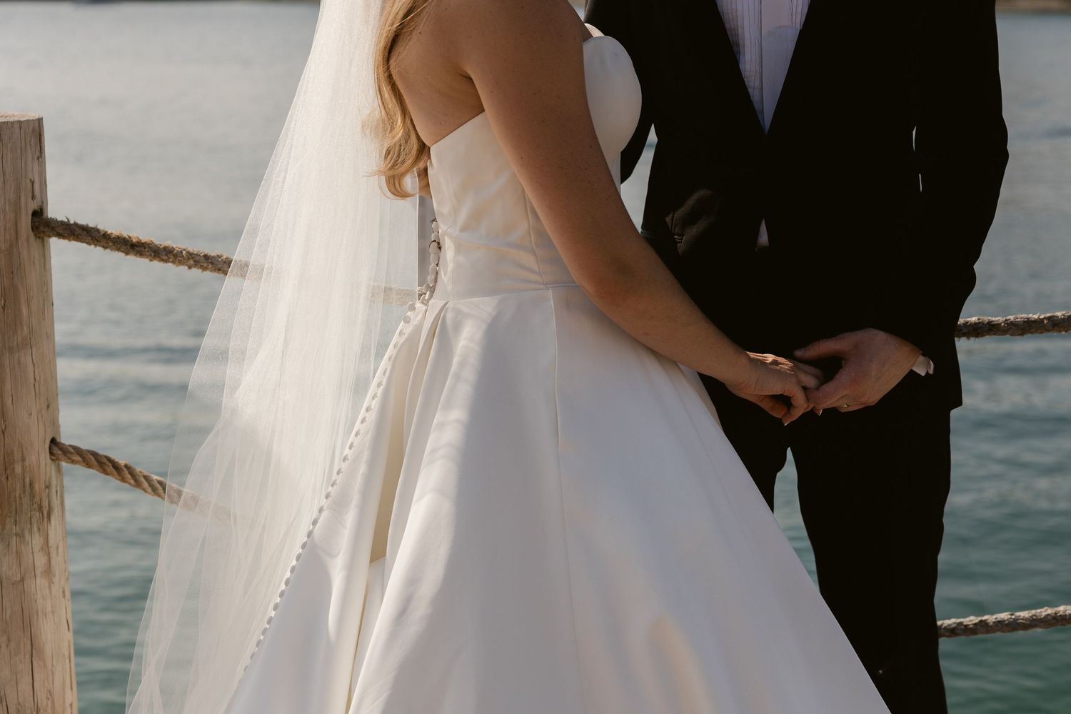Scenic waterfront wedding portraits with white dress flowing in the breeze.