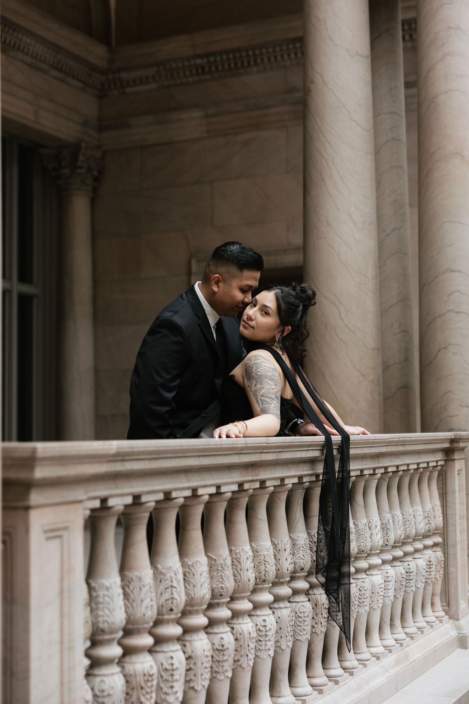 A romantic moment captured on an ornate balcony with classical columns and architectural details.