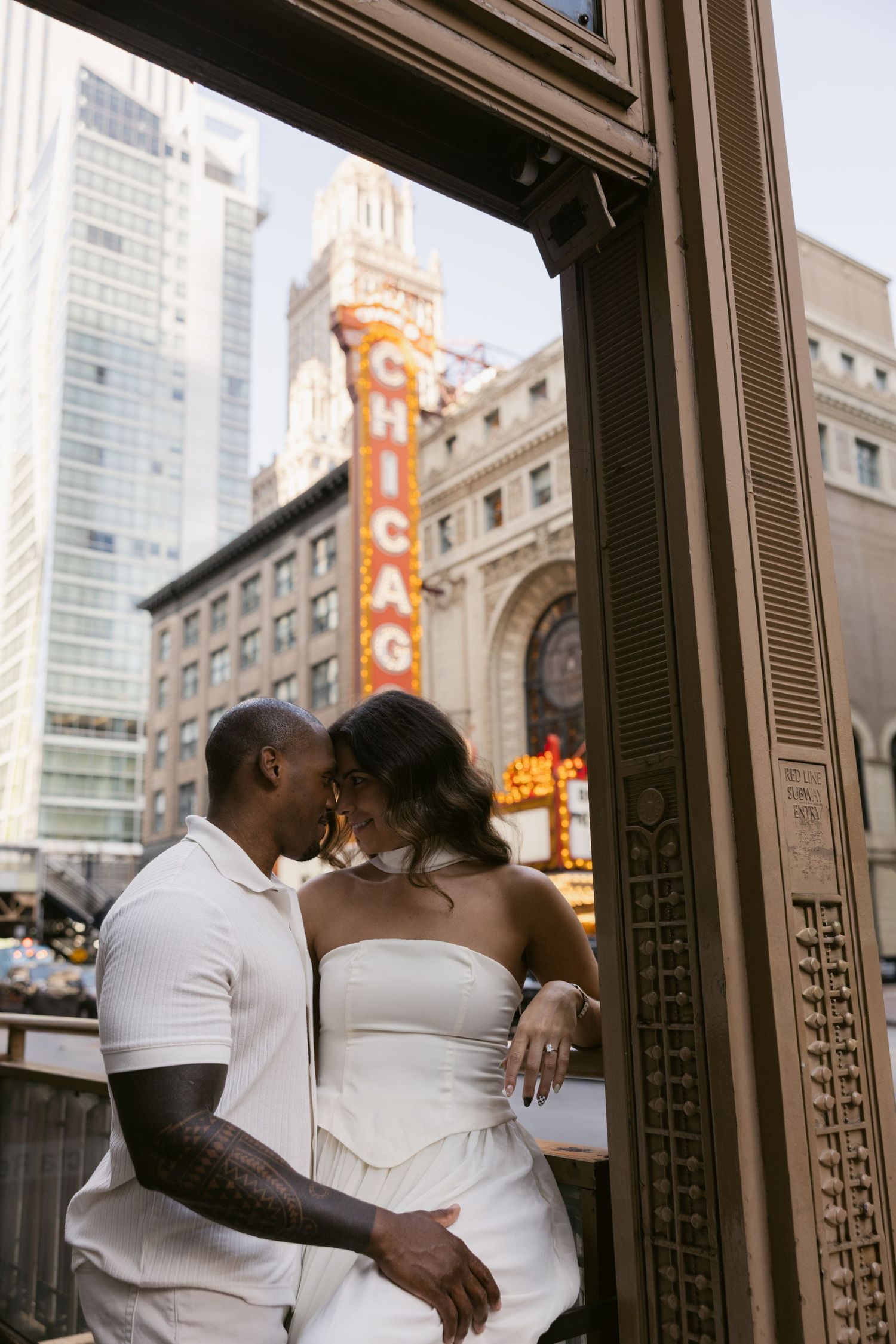 Romantic couple poses in front of historic Chicago Theatre marquee at dusk.