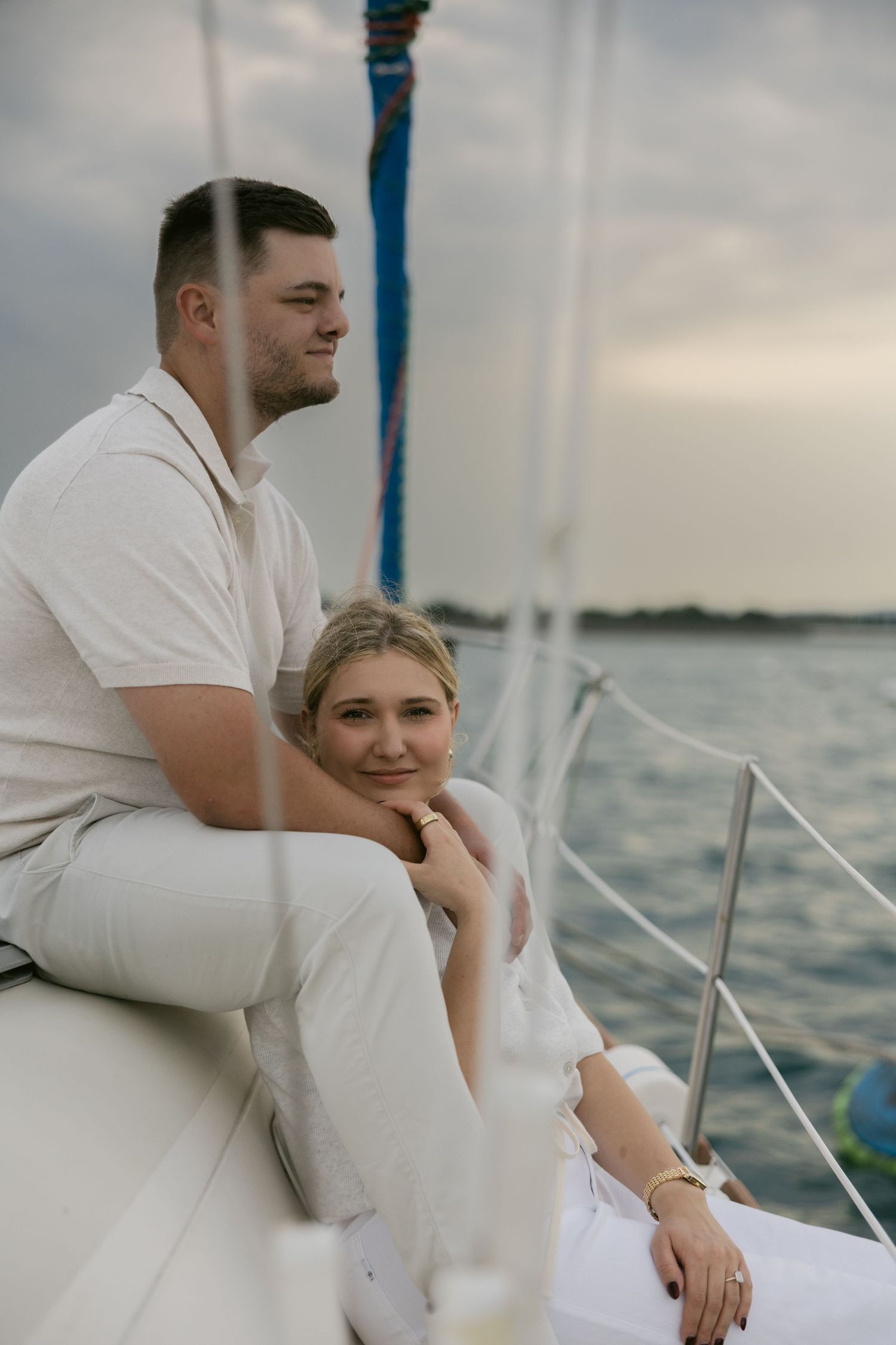 Relaxing sailing experience with two people in white attire against cloudy skies.