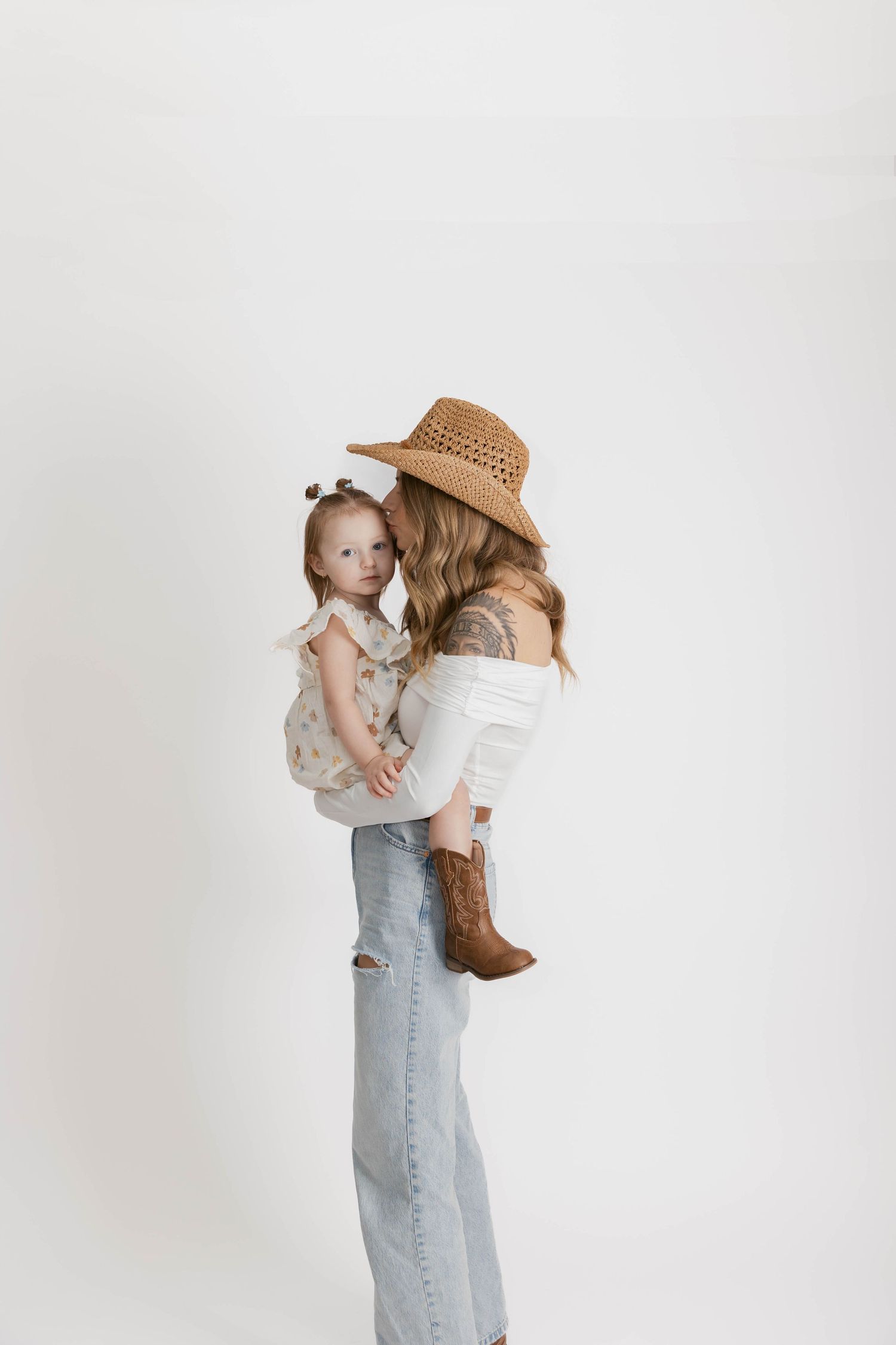 Sweet candid moment between parent and child in casual attire against white backdrop.