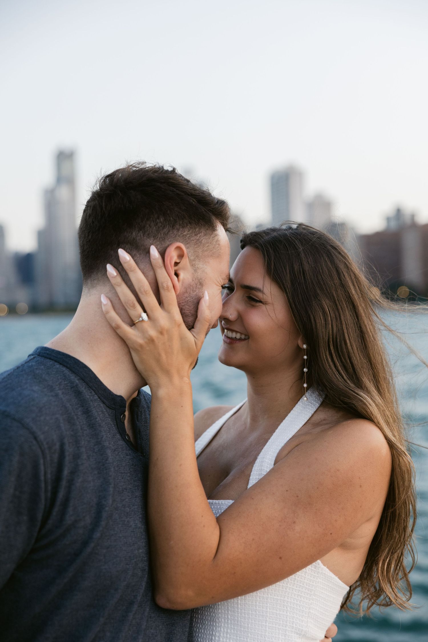 Intimate couple shares tender moments by Lake Michigan with Chicago's downtown architecture in background.