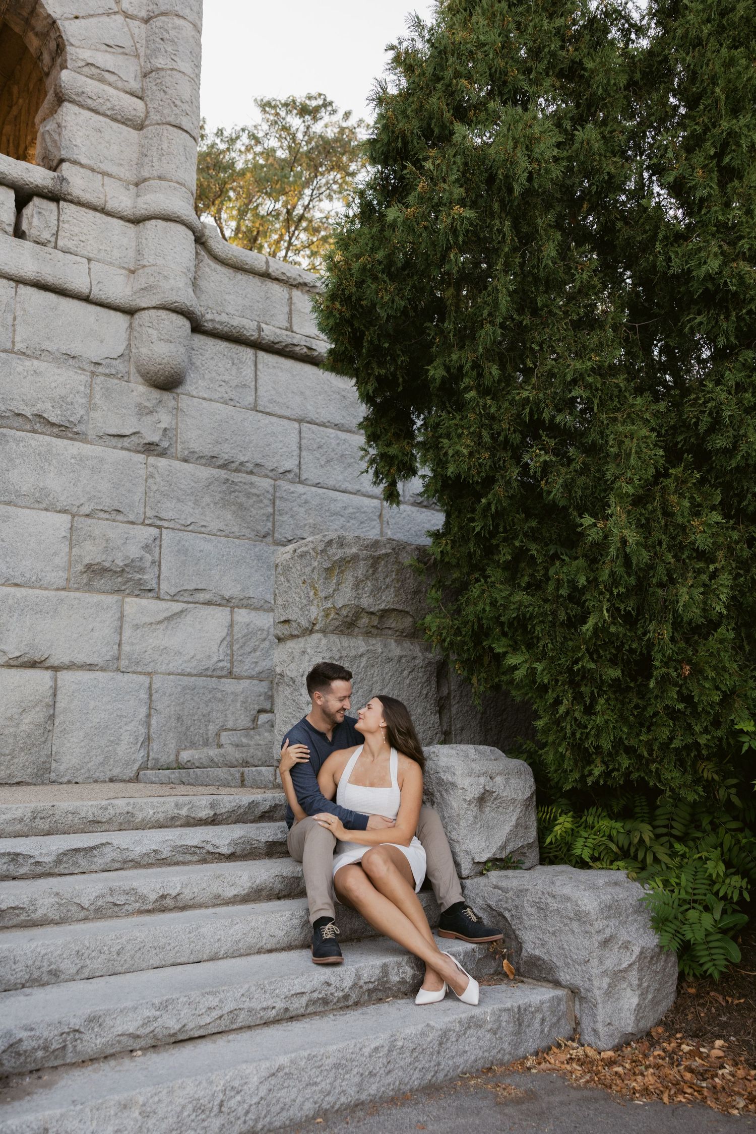 Couple sitting on stone steps sharing a playful moment outdoors.