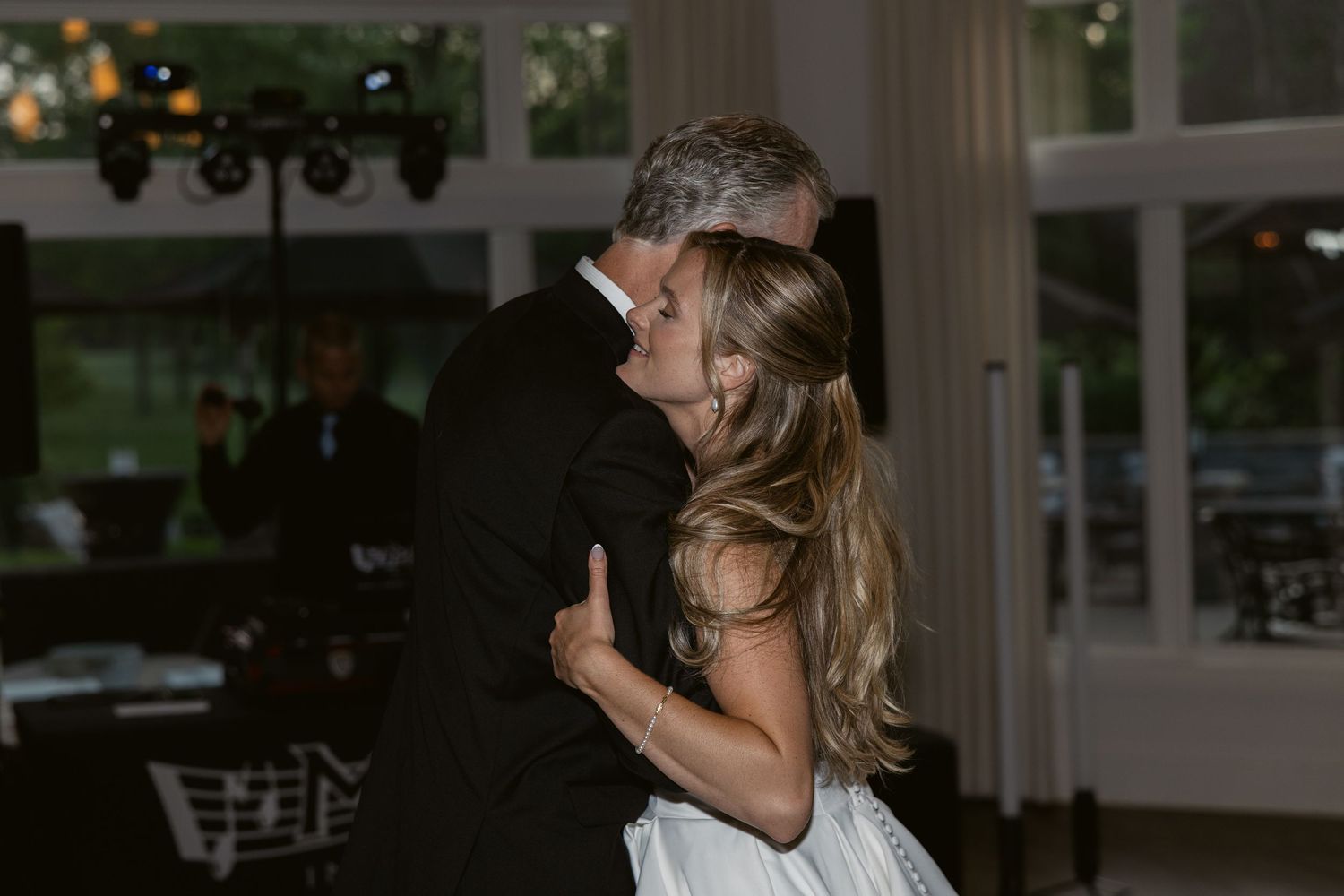 Reception guests dance in a dimly lit venue during evening celebration.