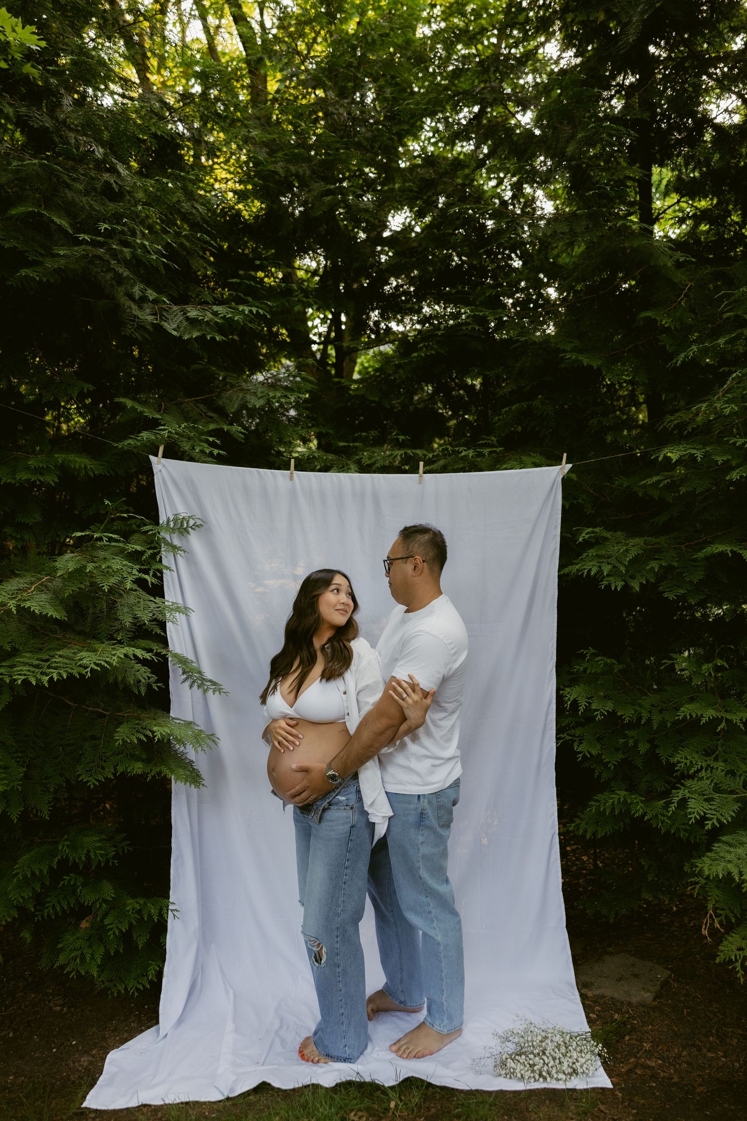 An intimate outdoor photoshoot featuring a couple against a hanging white sheet backdrop.
