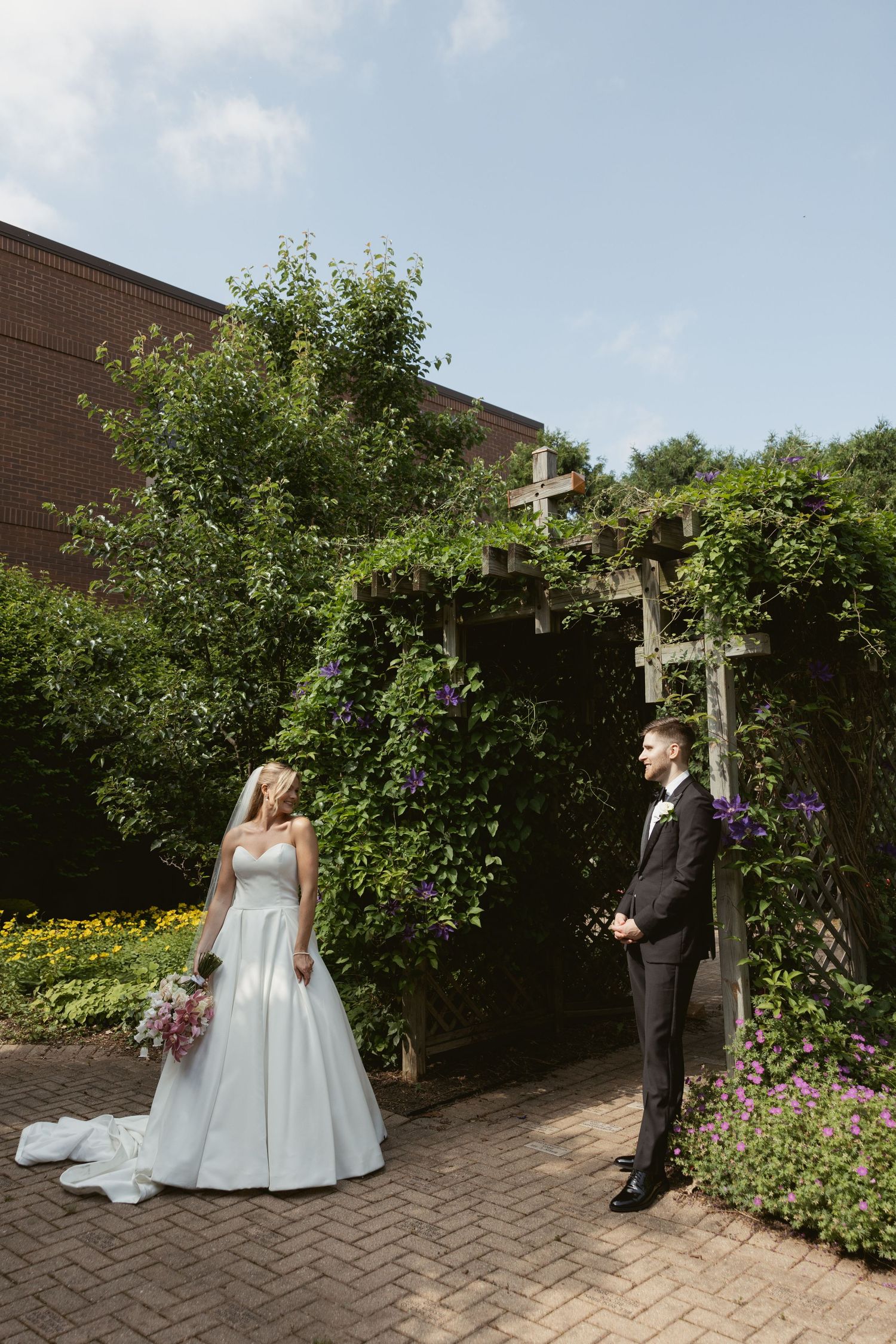 Elegant wedding ceremony location with floral arch and brick paved pathway in a garden.