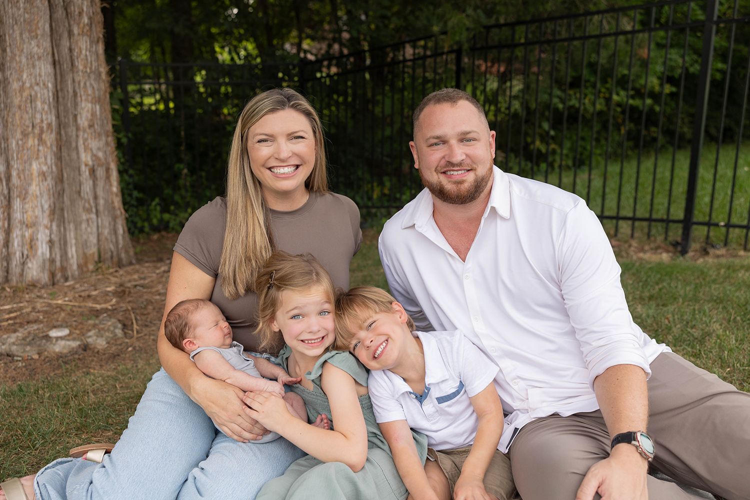 Family sitting together on grass for casual outdoor portrait session.